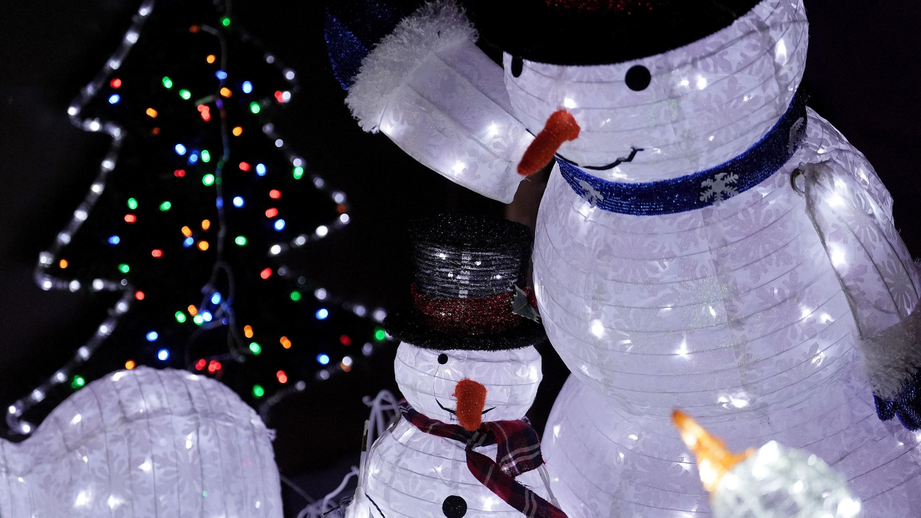 Two artificial snowmen and a brightly-lit Christmas tree