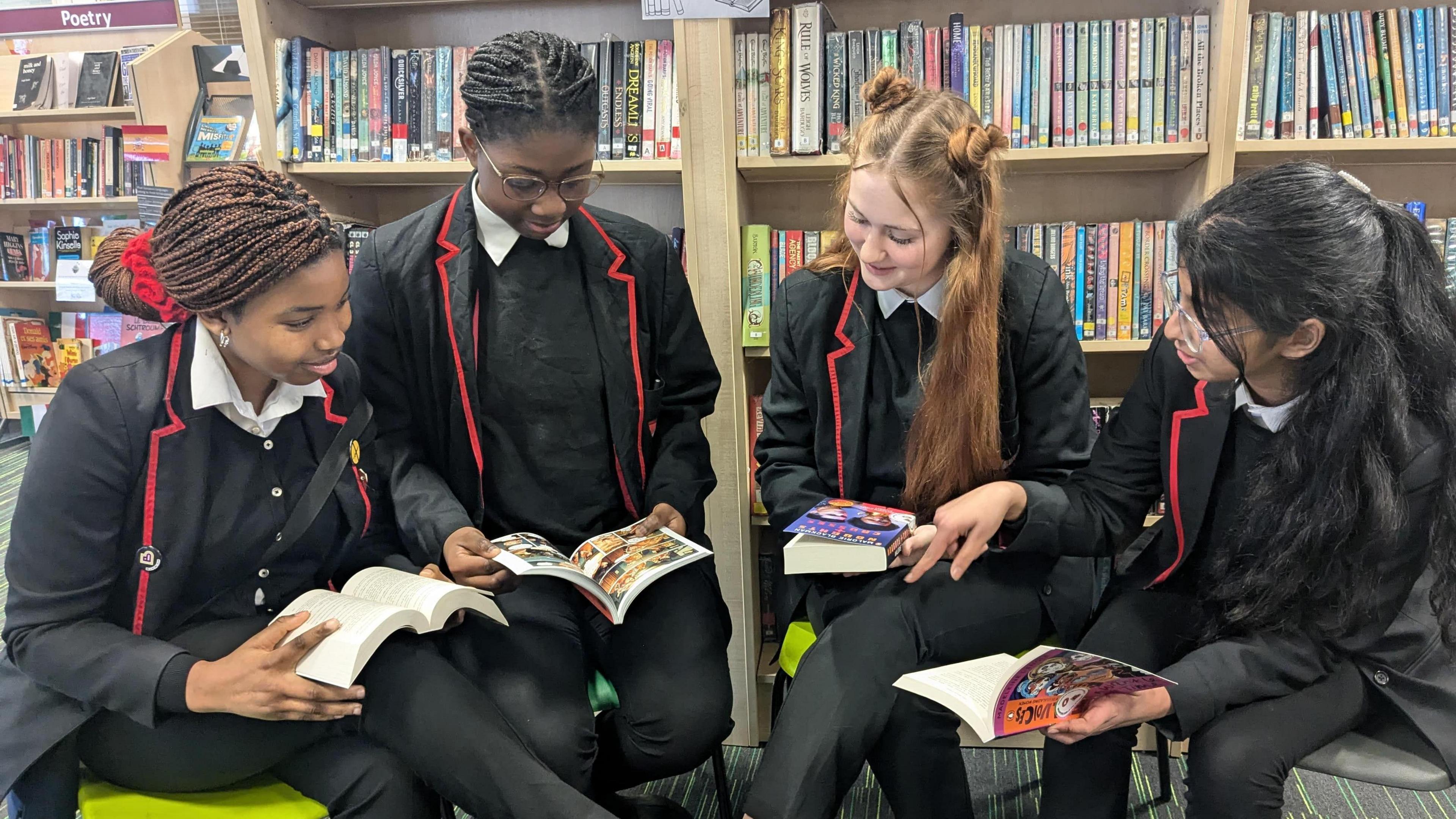 Four pupils in a school library sat reading different books together. 