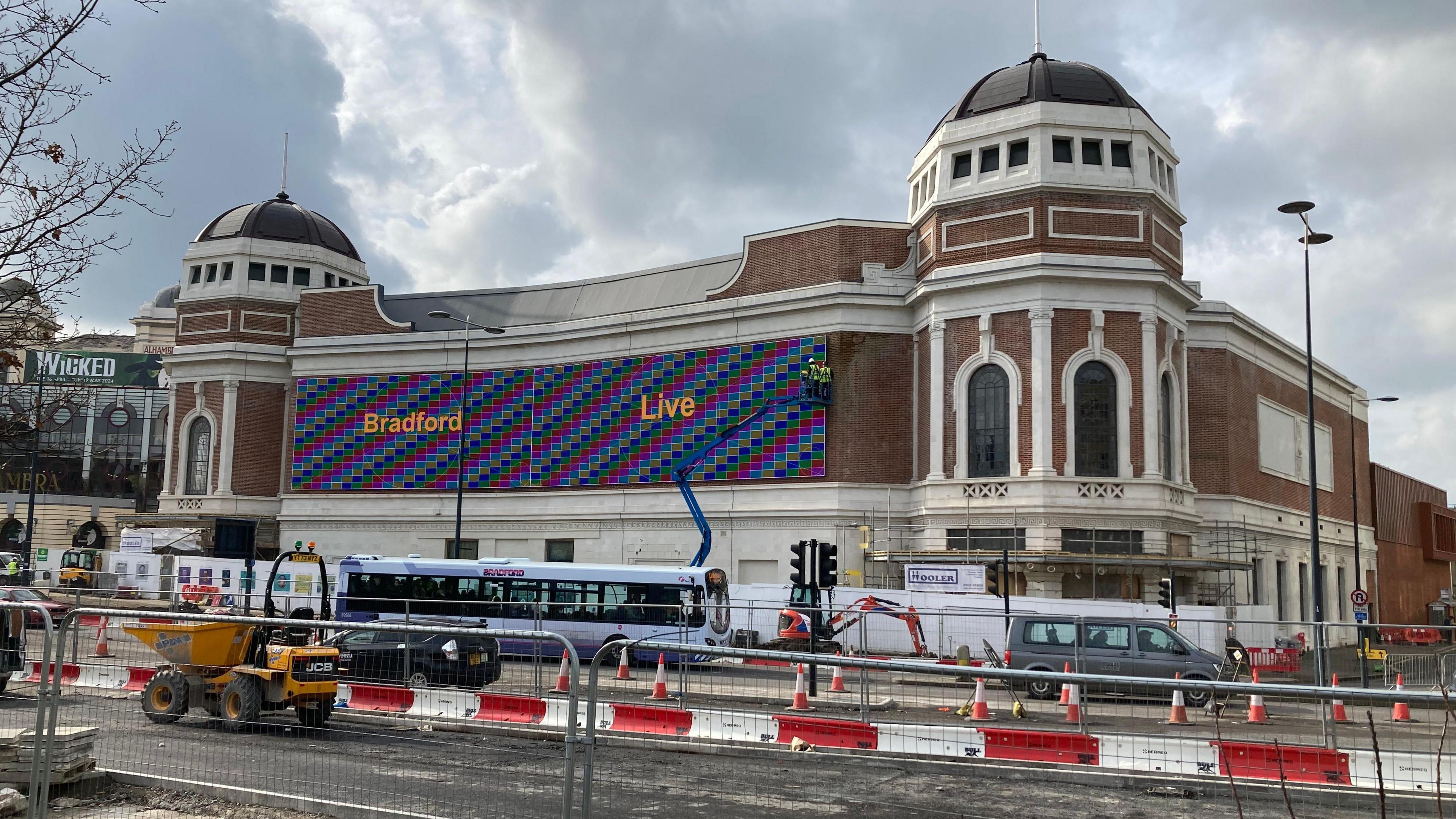 An exterior photo of the Bradford Live building in central Bradford, with roadworks taking place in the foreground and vehicles negotiating diversions. 