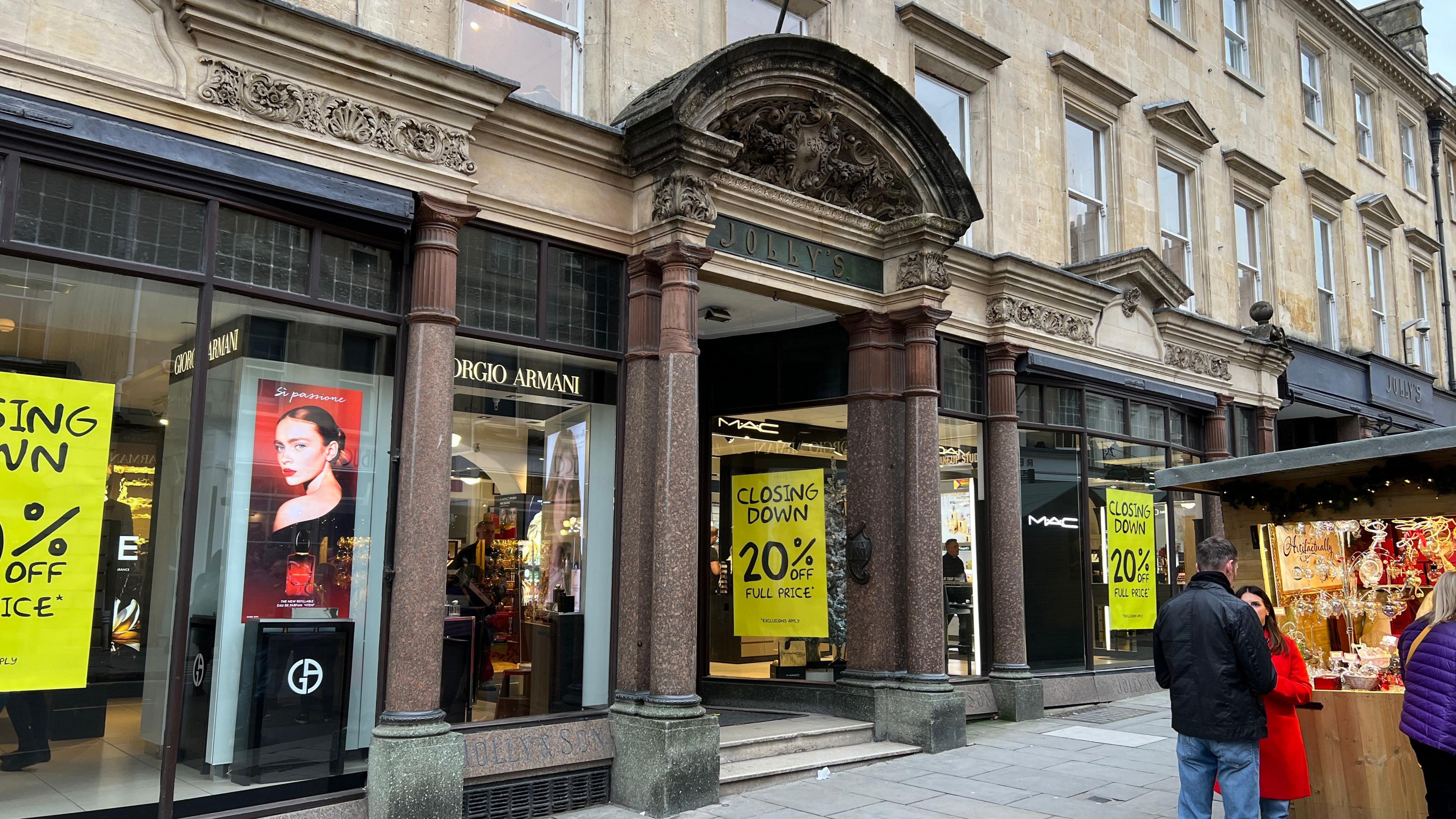 Image shows the outside of the department store Jolly's, with yellow 'Closing Down' signs in the windows. 