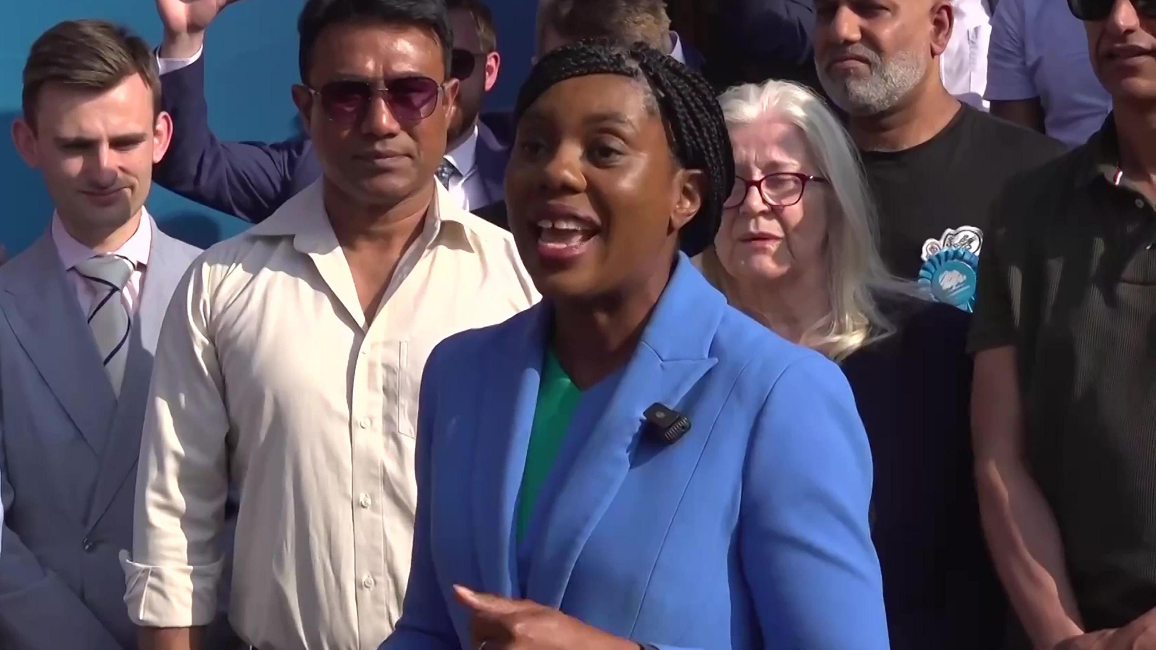 Kemi Badenoch wearing a blue suit surrounded by supporters