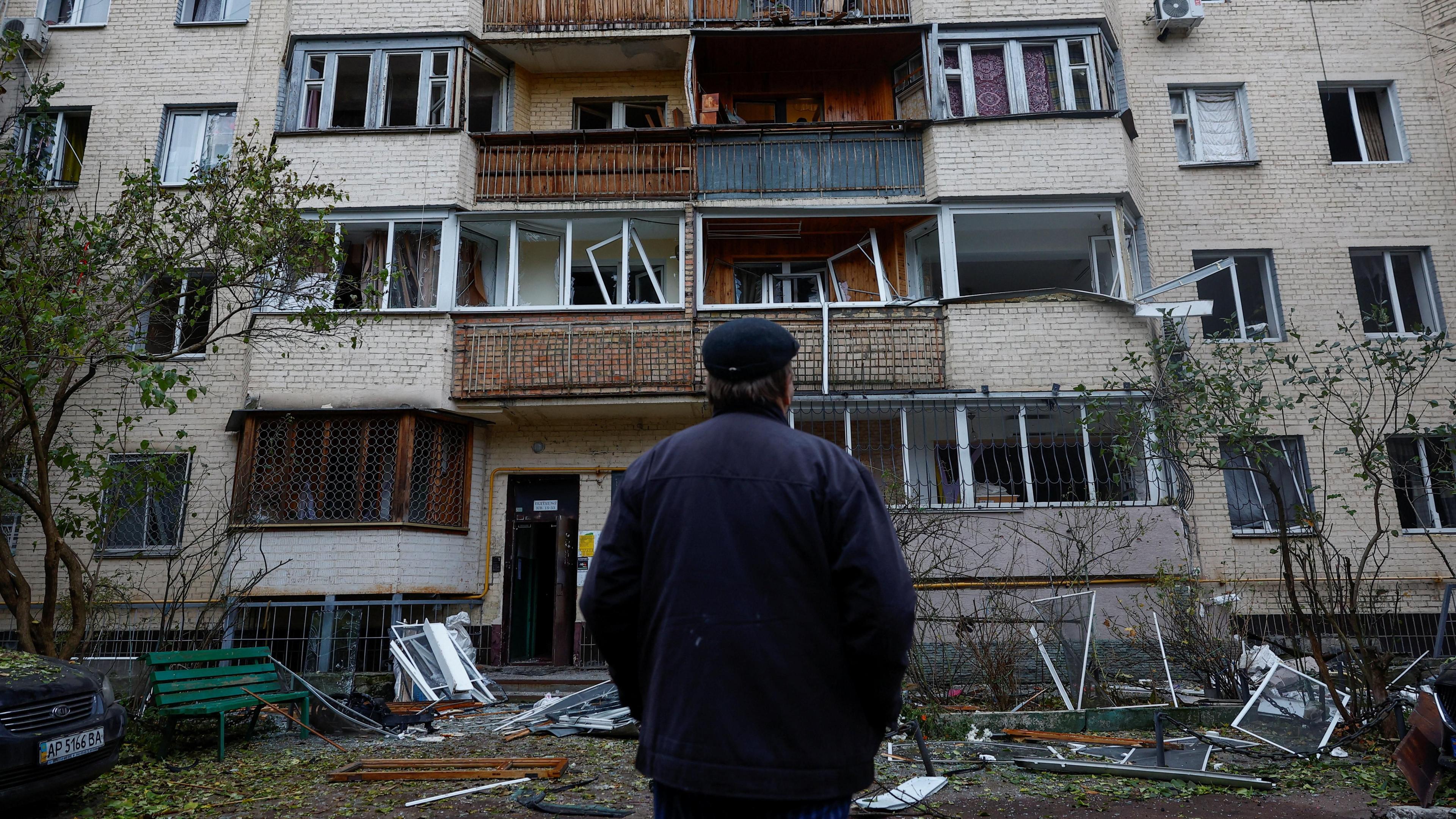A man looks at a destroyed building in Kyiv