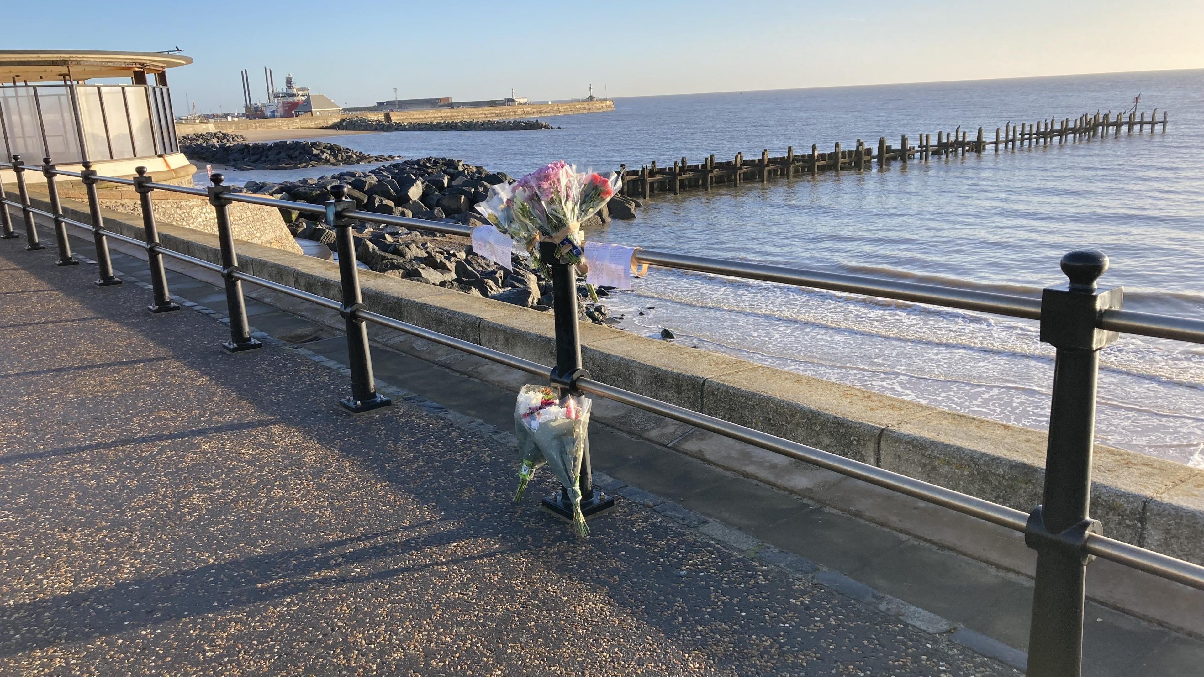 FLowers and tributes along a sea wall and barrier