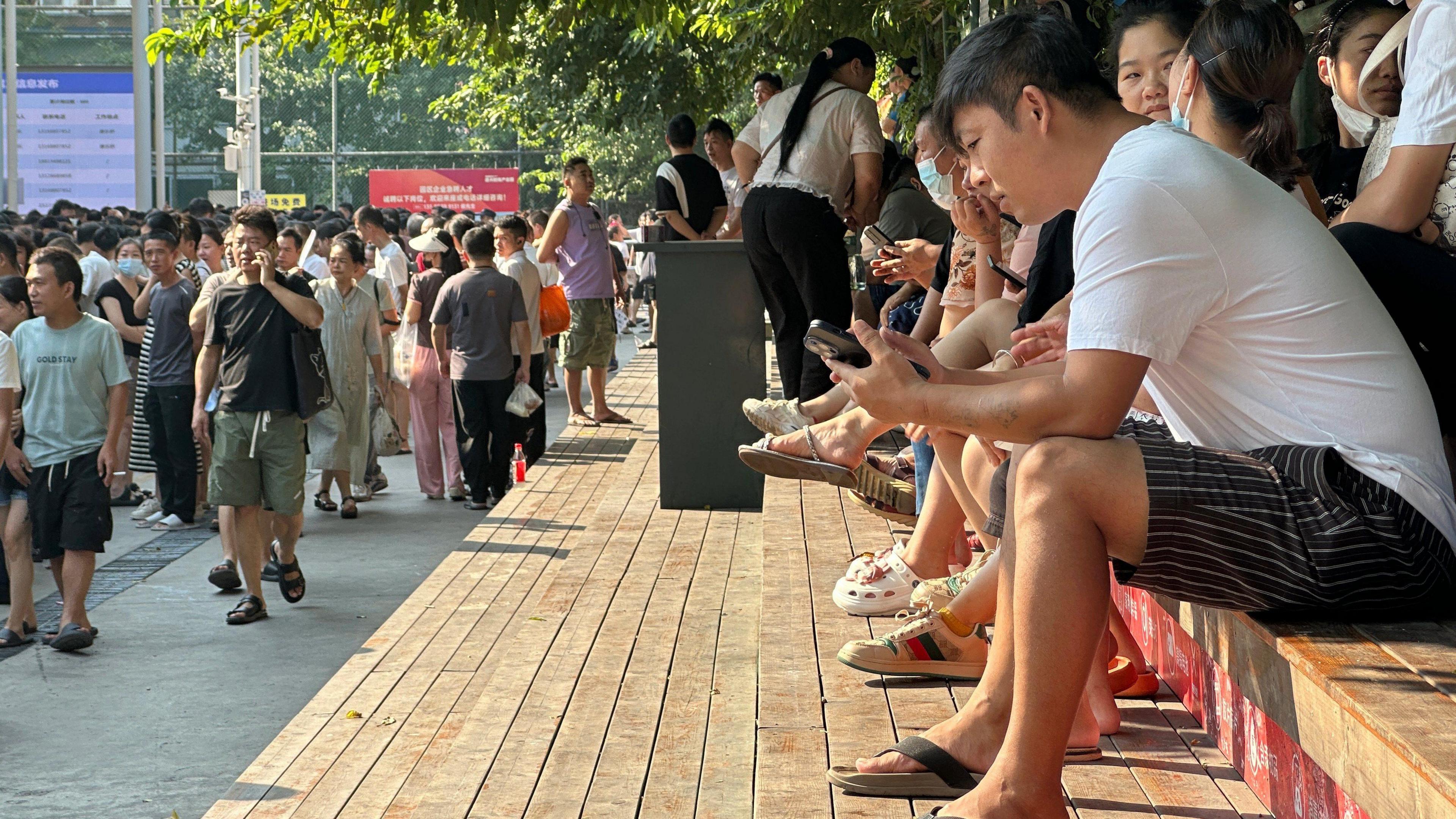 Crowds at a job market in Guangzhou city - people sit in rows on steps, while a crowd walks past.  