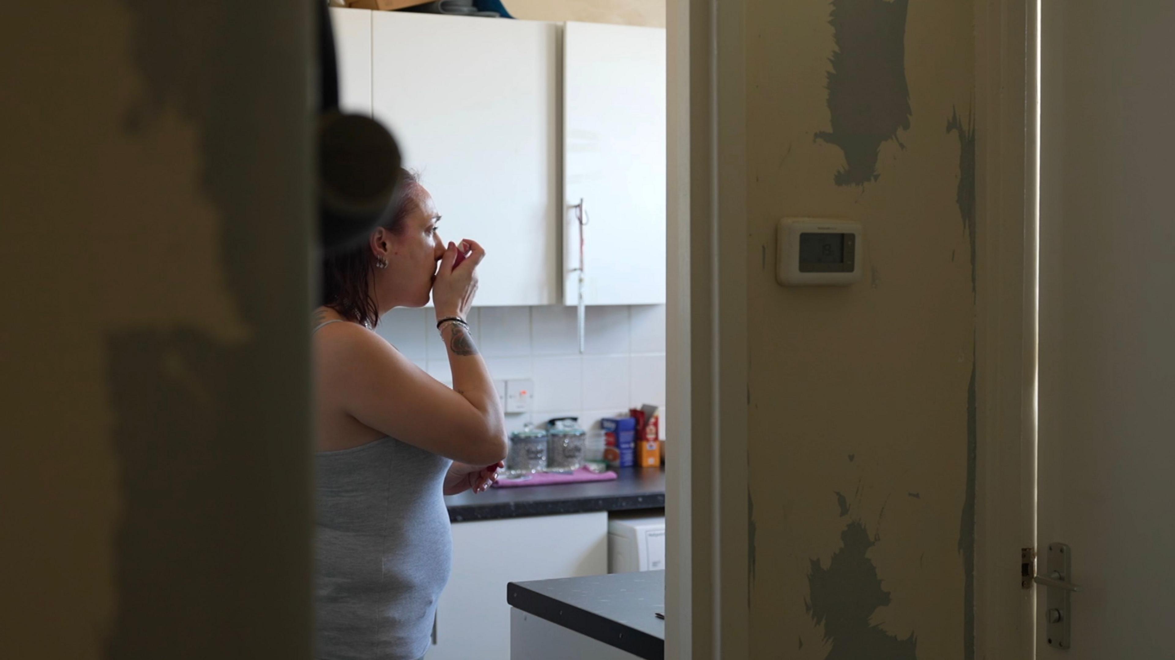 Stacey Coveley using an inhaler in her kitchen