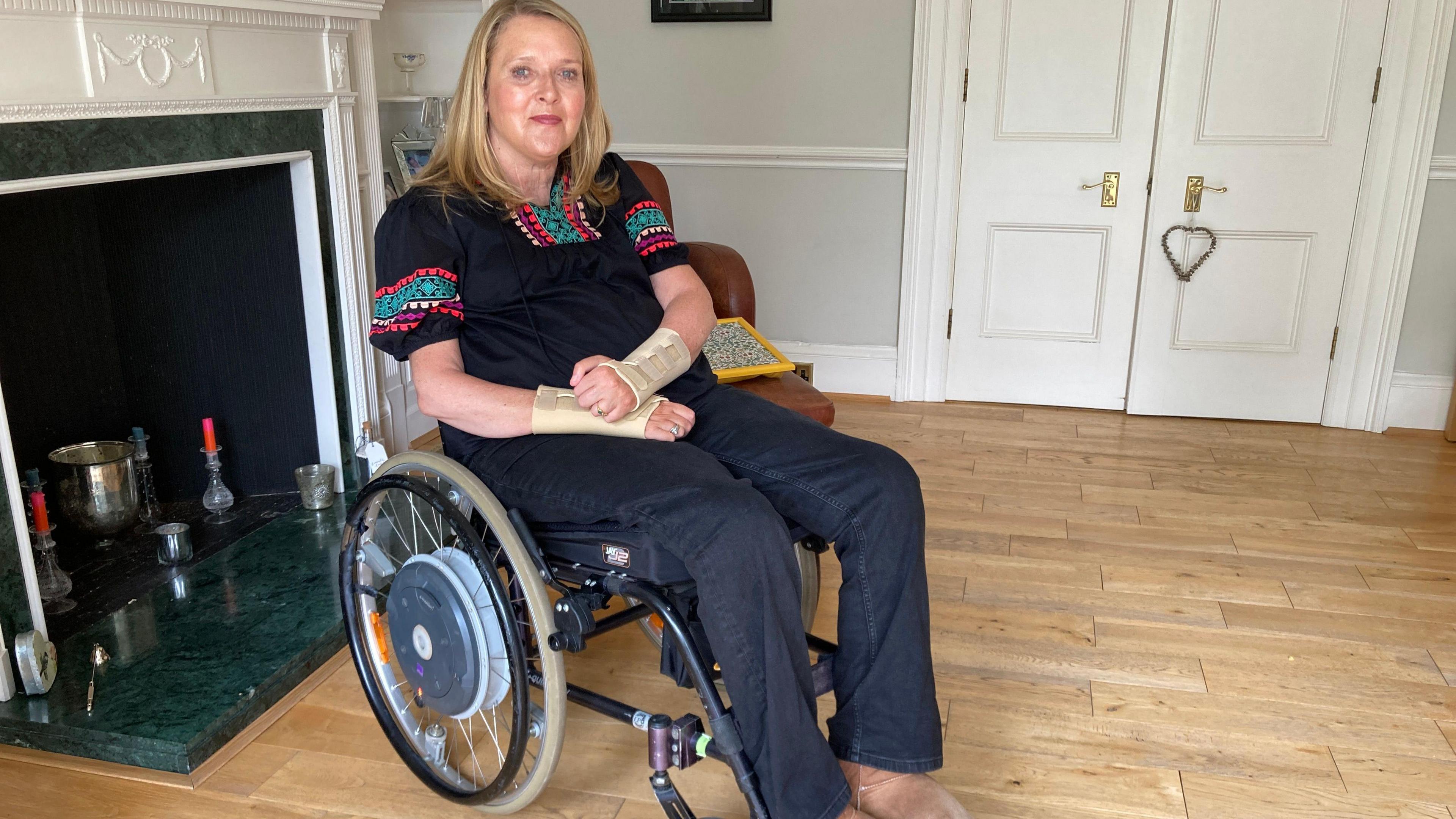 Jane Hudson sits in wheelchair in her front room