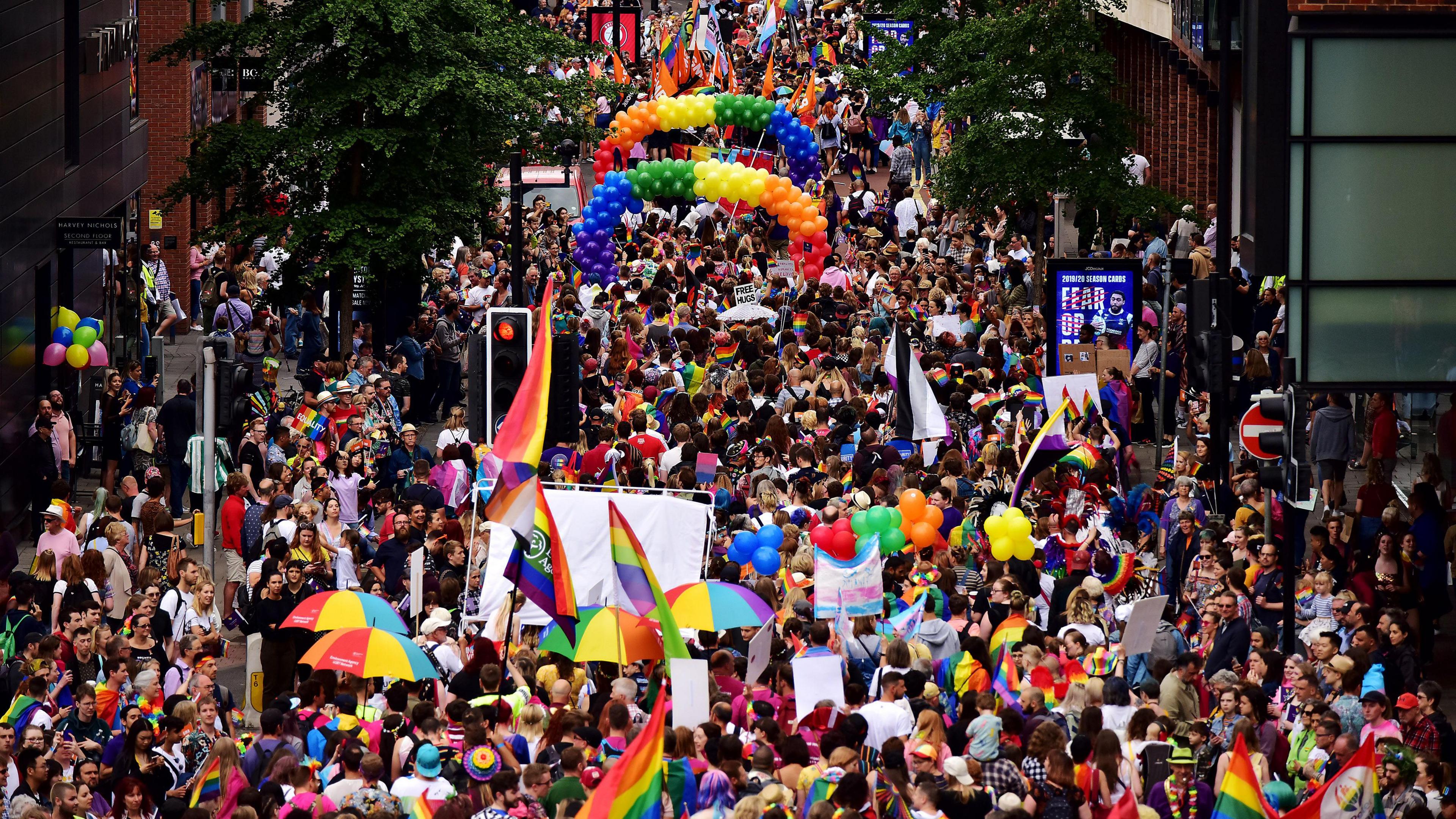 A wide view of the parade moving through central Bristol, with rainbow flags and umbrellas.