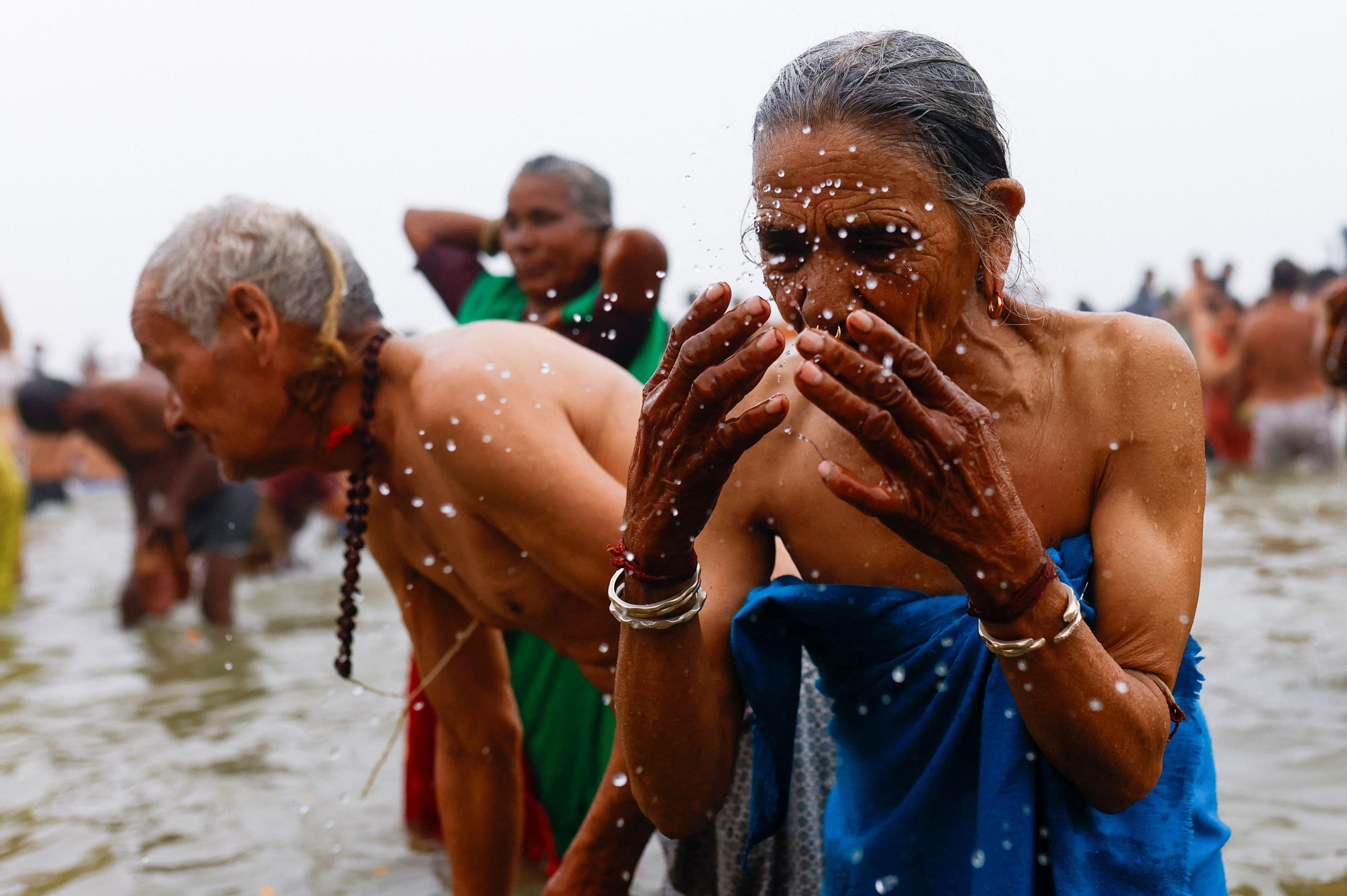 A woman splashes herself with the water.