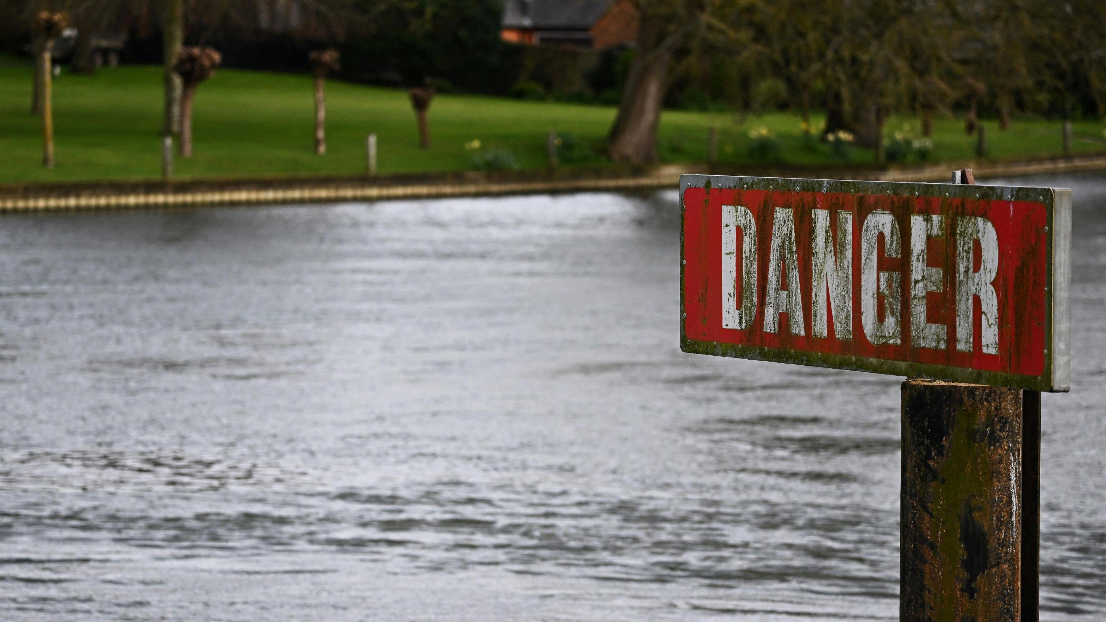 A sign reading "danger" next to the River Thames