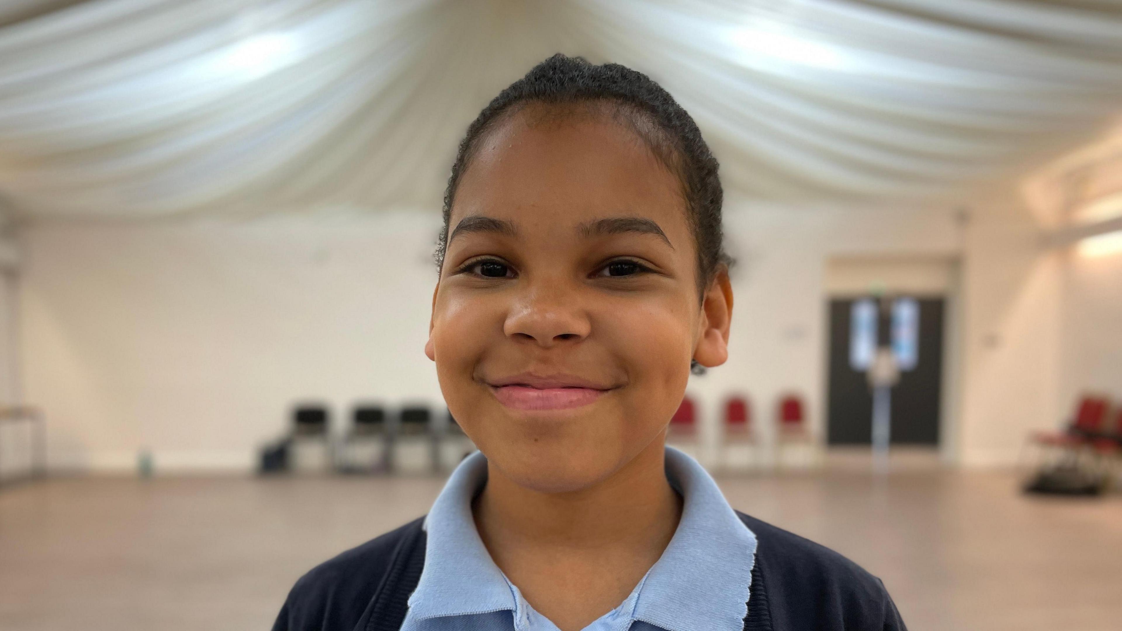 Nashea in school uniform standing in a hall