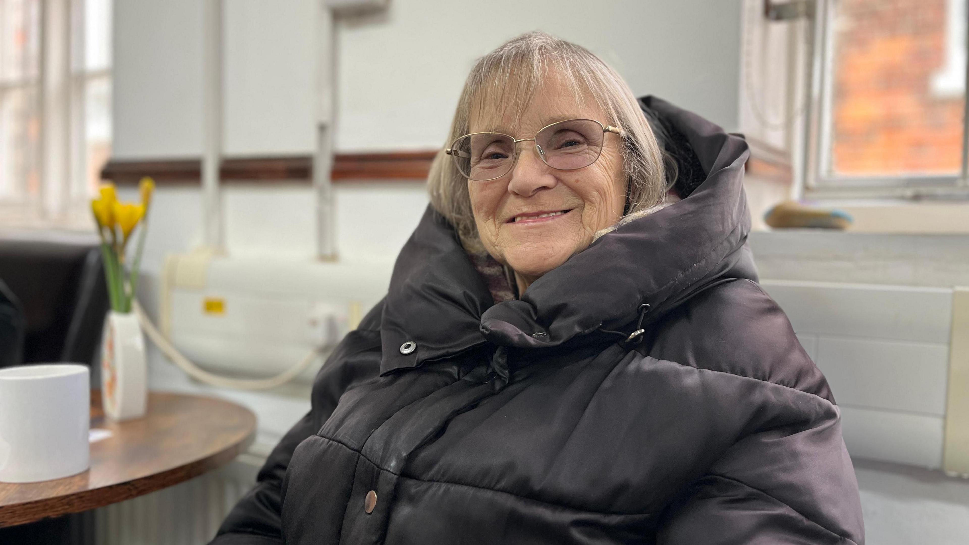 Rita Wilcock sitting with a mug on a table next to her.