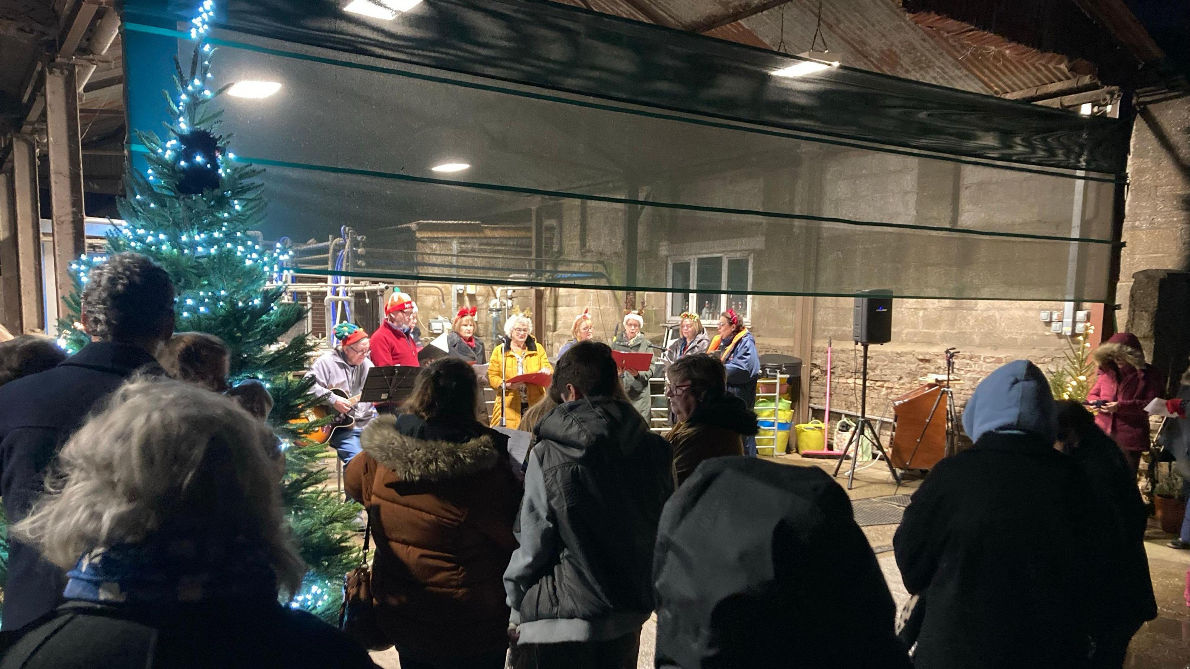 People listening to a Carol service in a farm barn