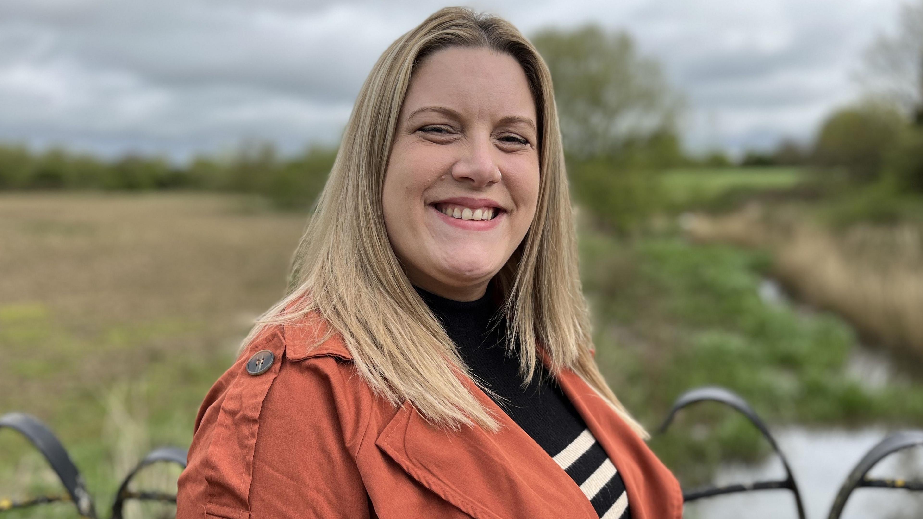 Melksham Town Councillor, Jennie Westbrook, smiling in front of the land Melksham Green Space attempted to secure for the community