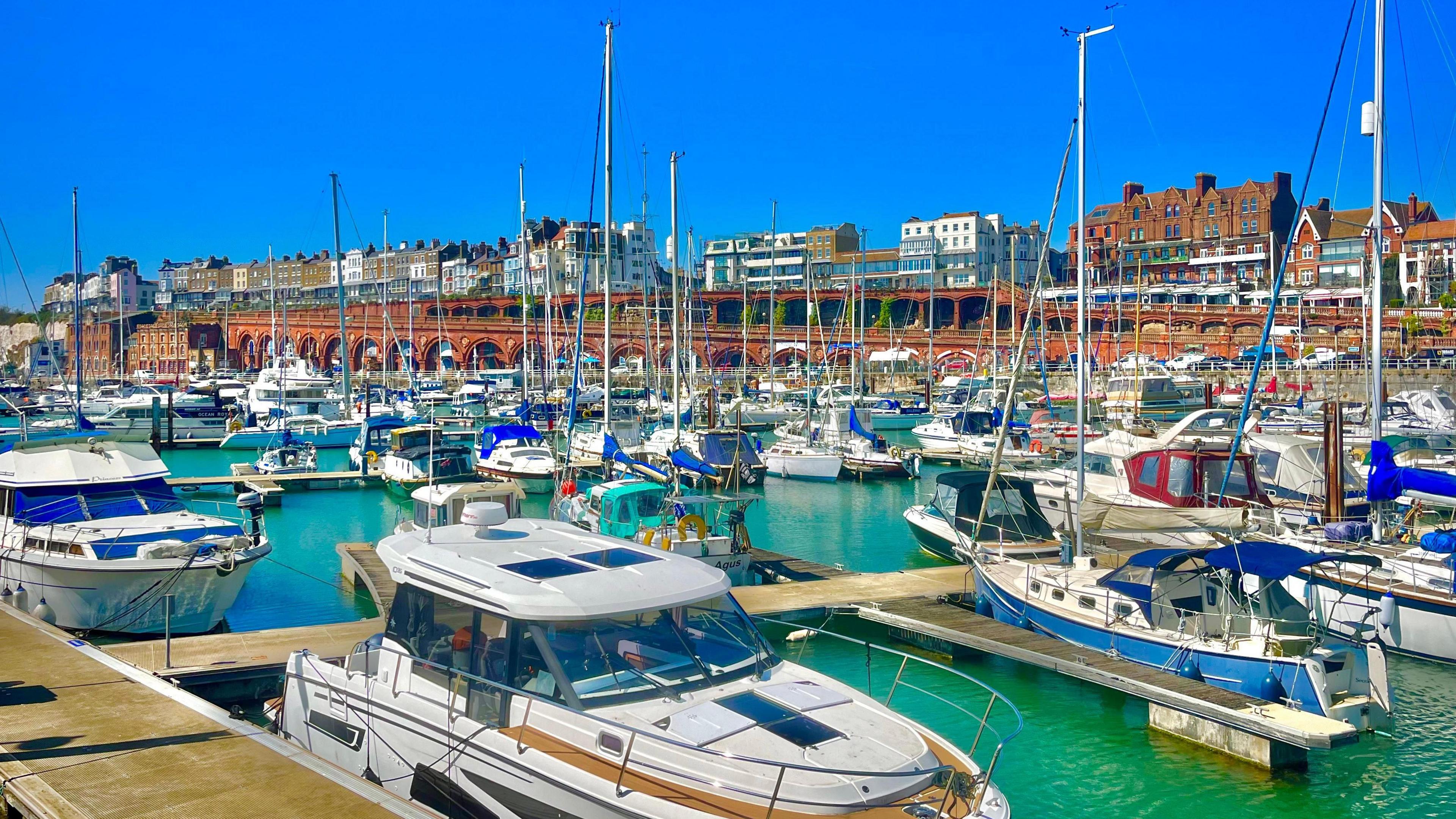 A harbour filled with speed boats with bright blue sky above 