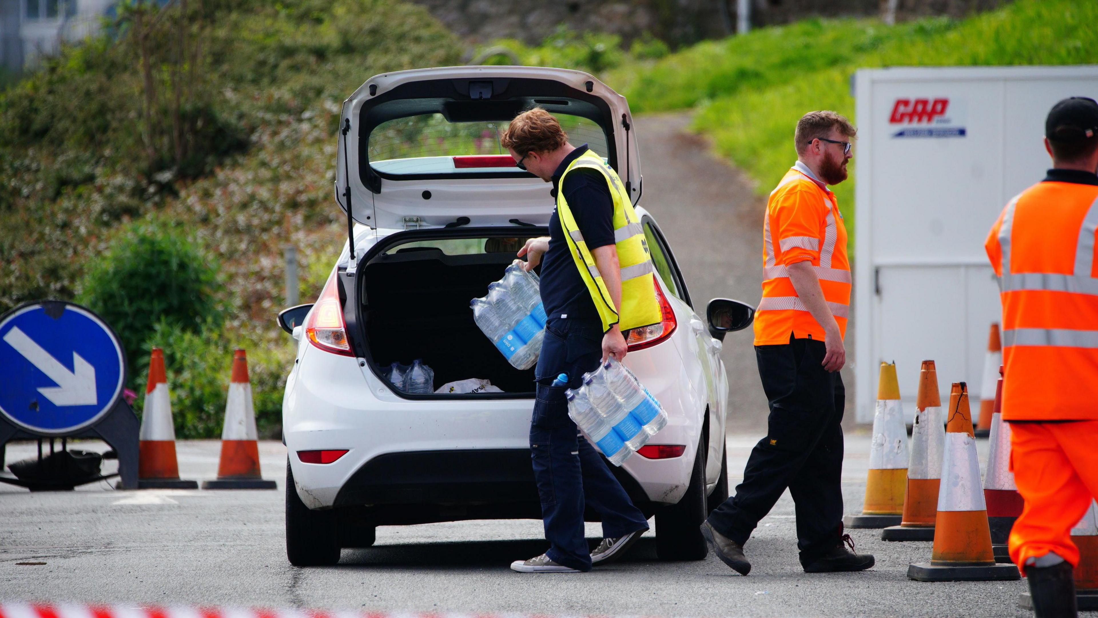 A man loads bottled water into a car