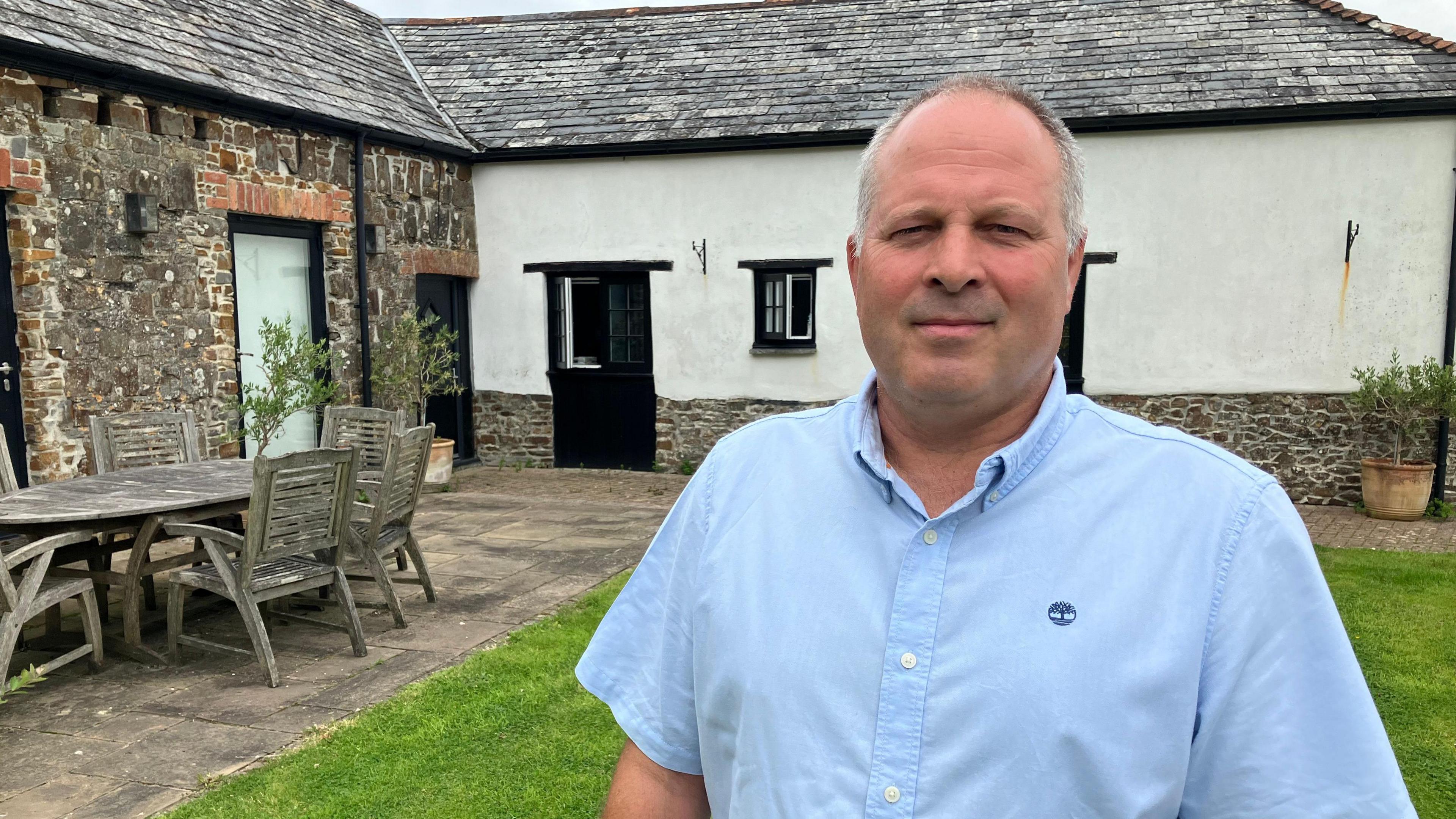 Man standing in front of stone holiday cottage 