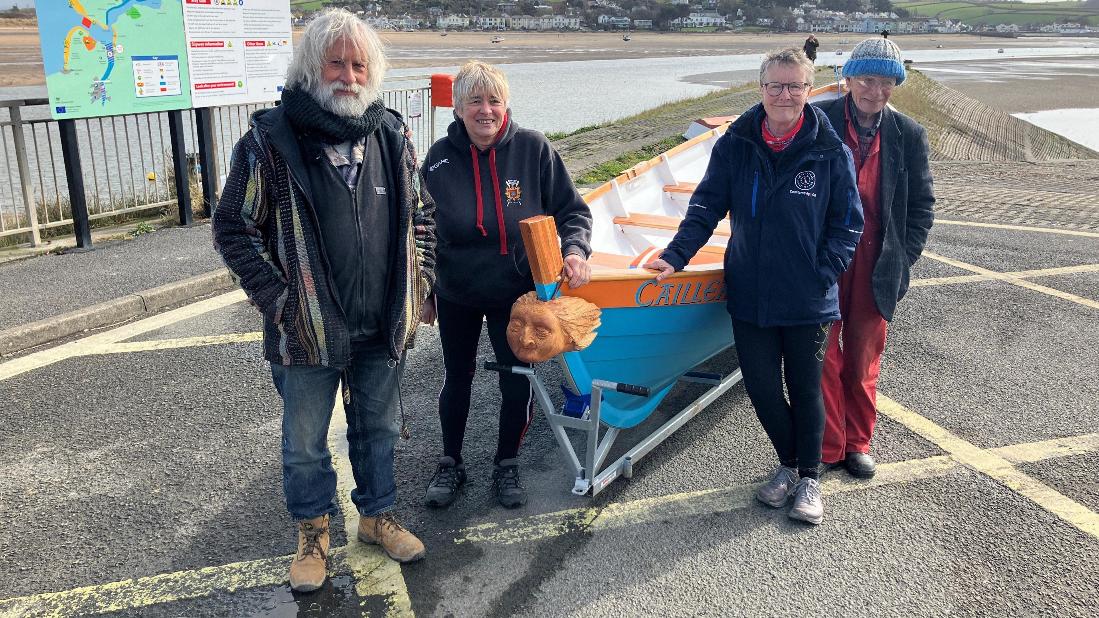 The four boat builders stood by the skiff. 