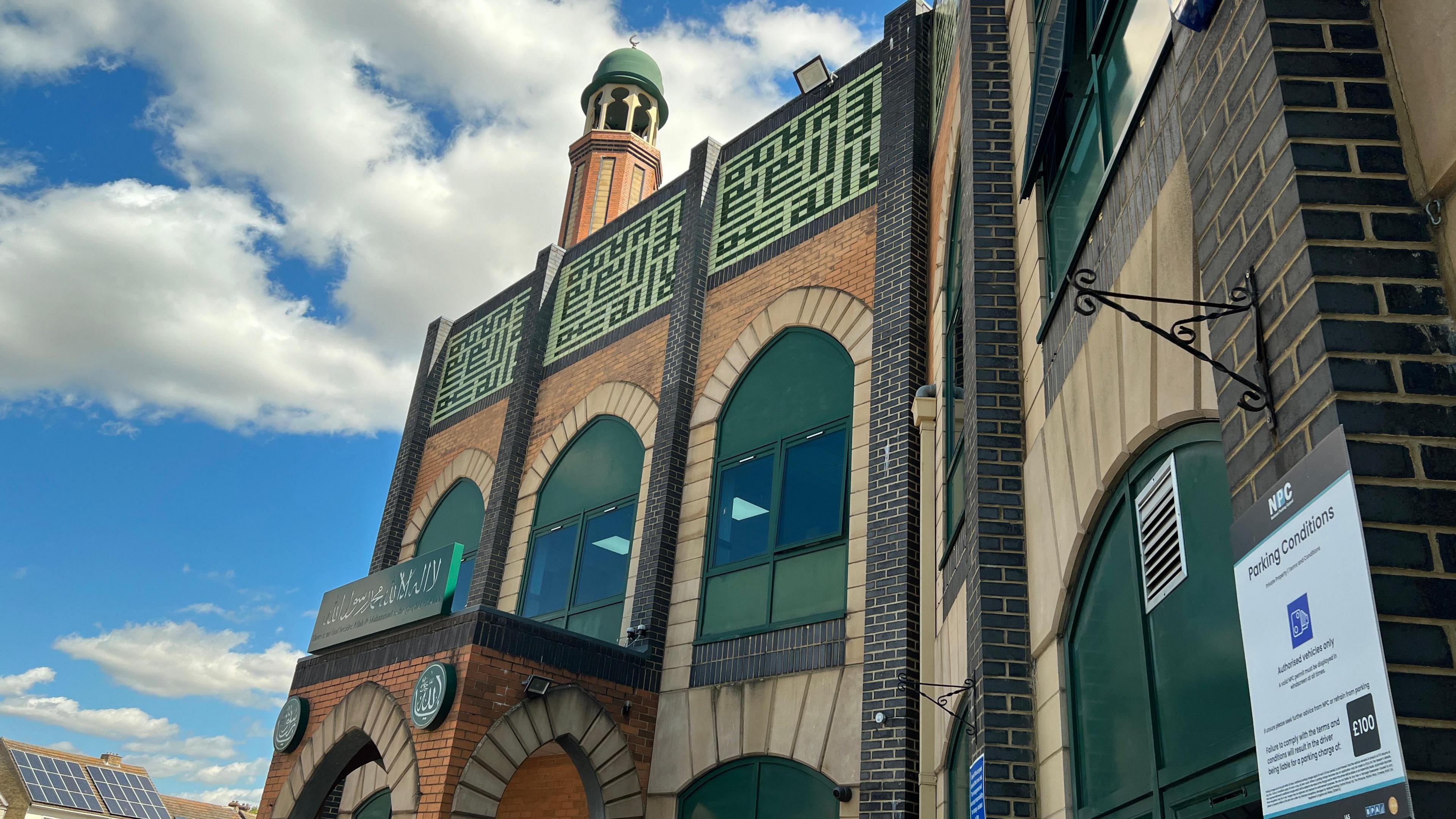 The facade of Faizan-e-Madina mosque including large green windows and an opening archway.
