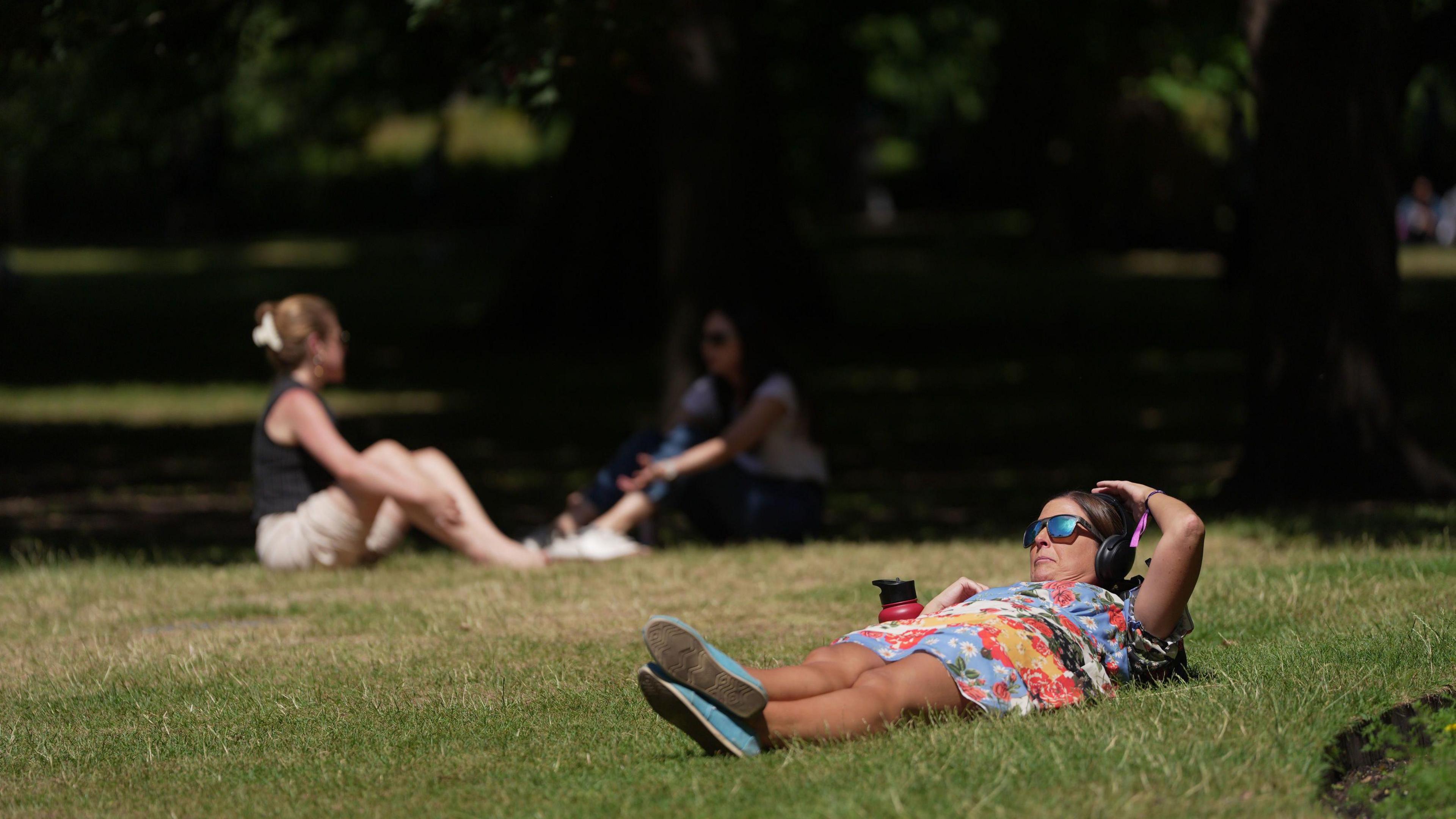 People lounging in the sun on the grass in St James Park in London 