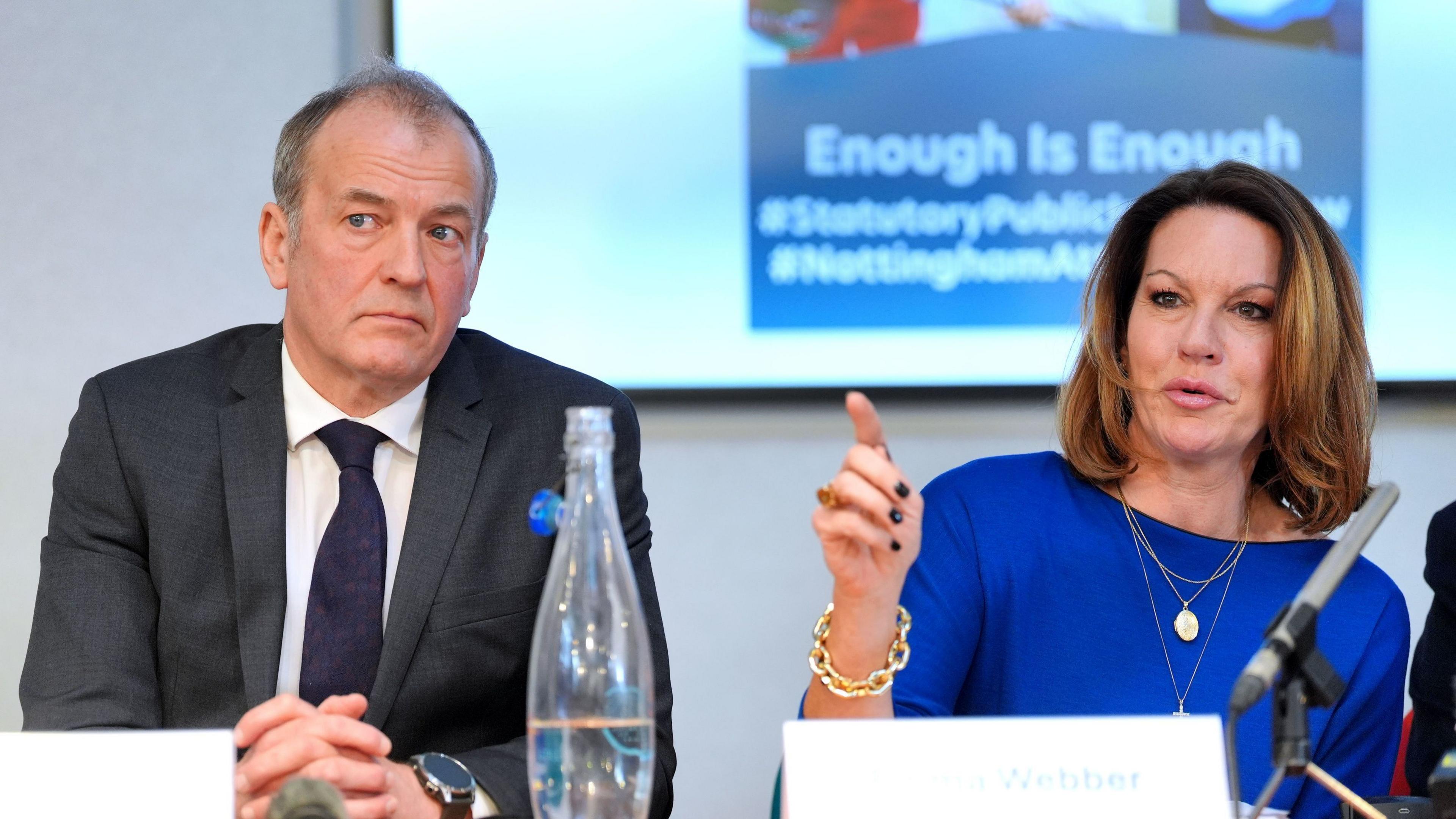 A man in a suit next to a woman in a blue dress.