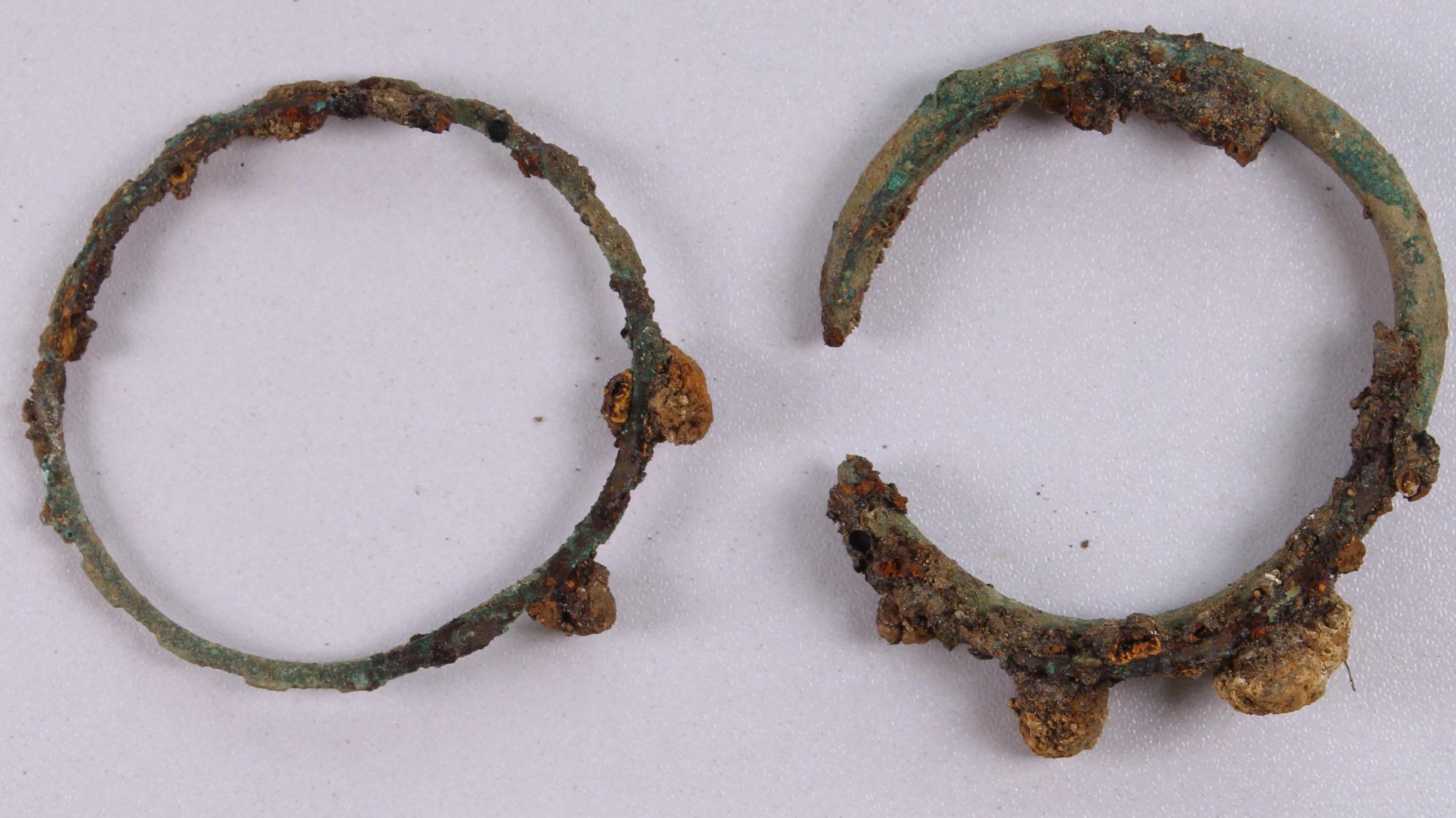 Two copper alloy bracelets side by side showing signs of corrosion