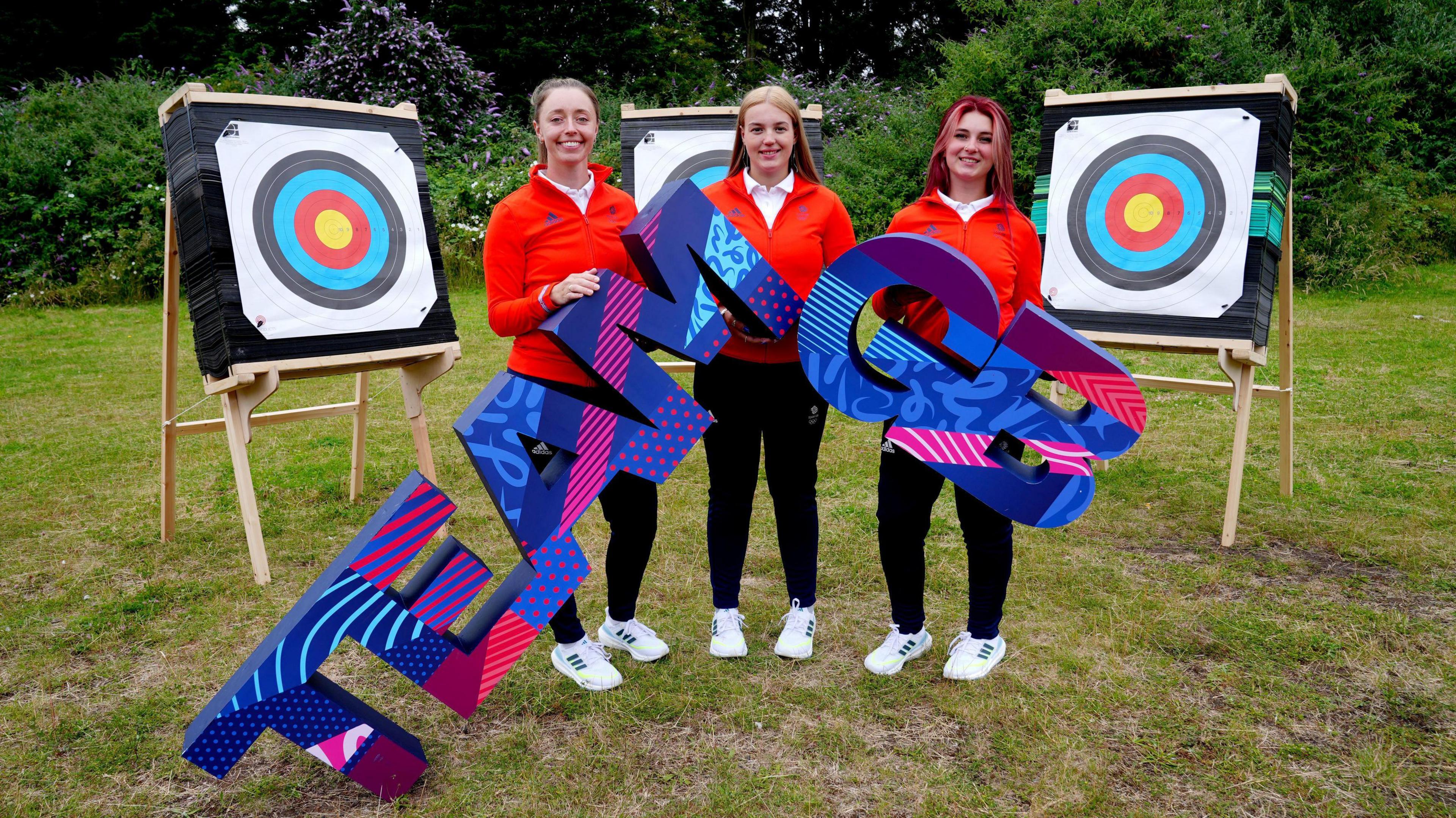 Megan (middle) with her teammates Bryony Pitman (left) and Penny Healey (right) holding Team GB words and in front of targets