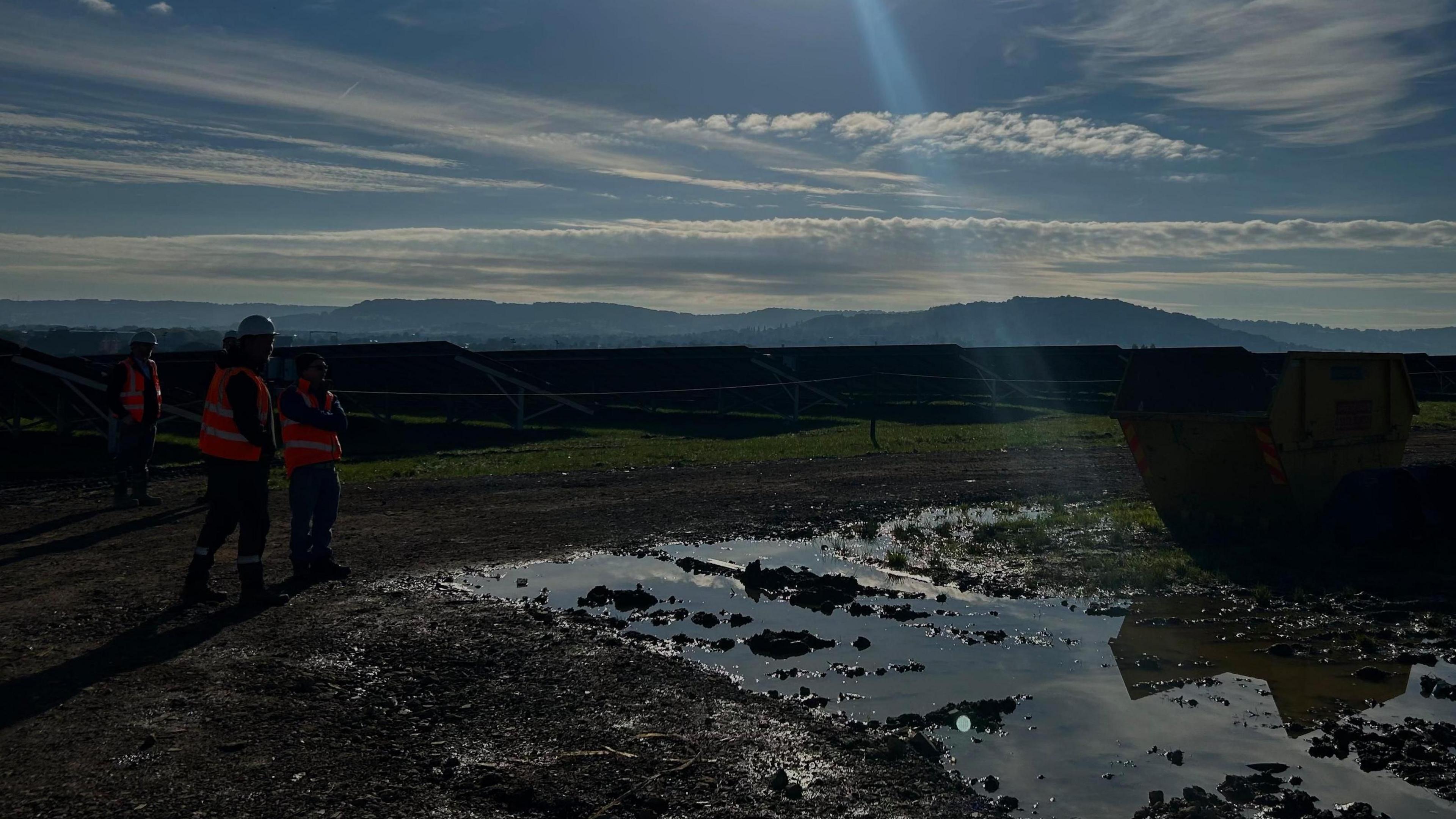 Workers positioned in front of solar panels at the Hempsted landfill site being turned into an ecopark.