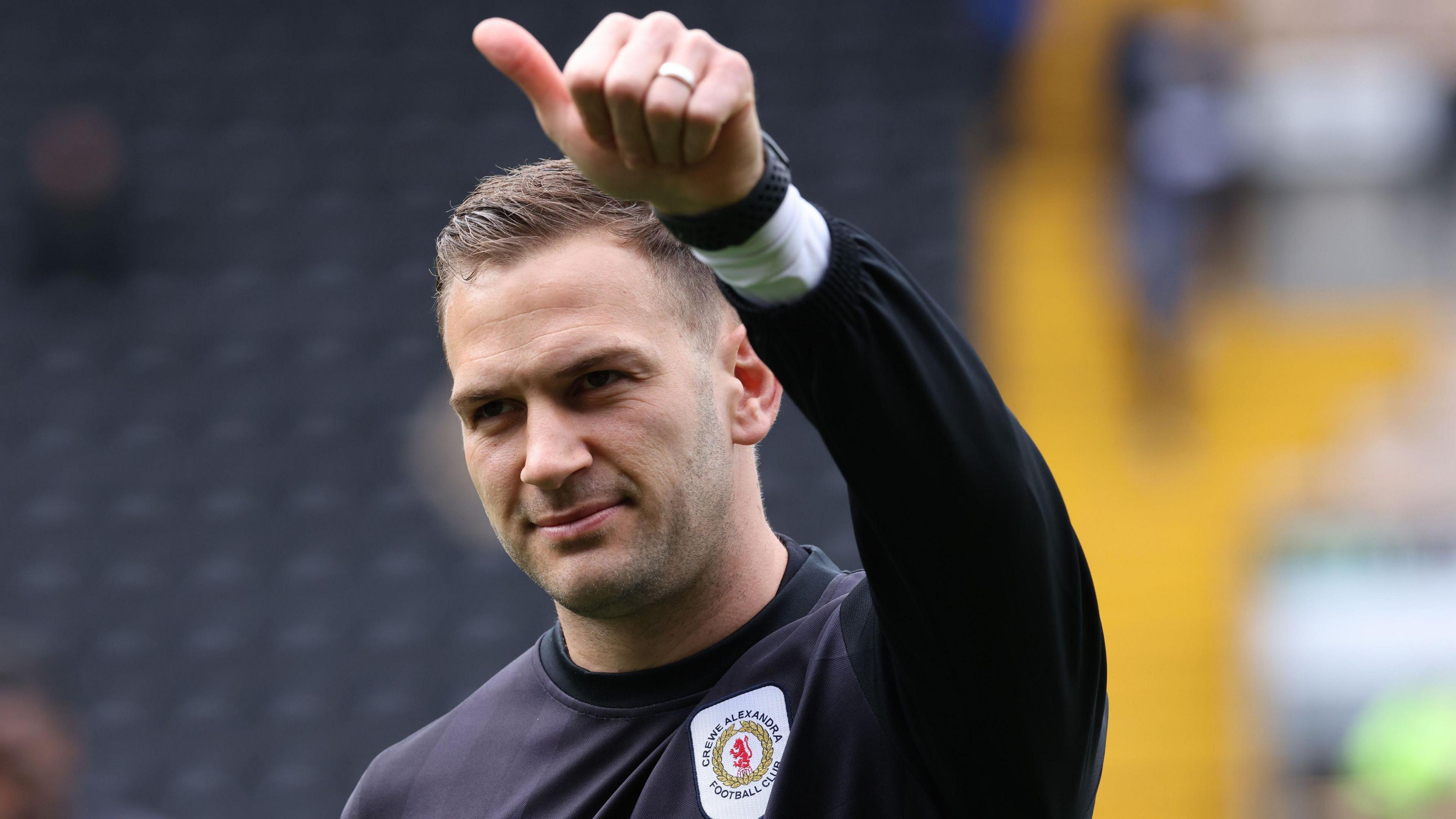 Crewe's Mickey Demetriou gives a thumbs up to the crowd during a pre-match warm-up