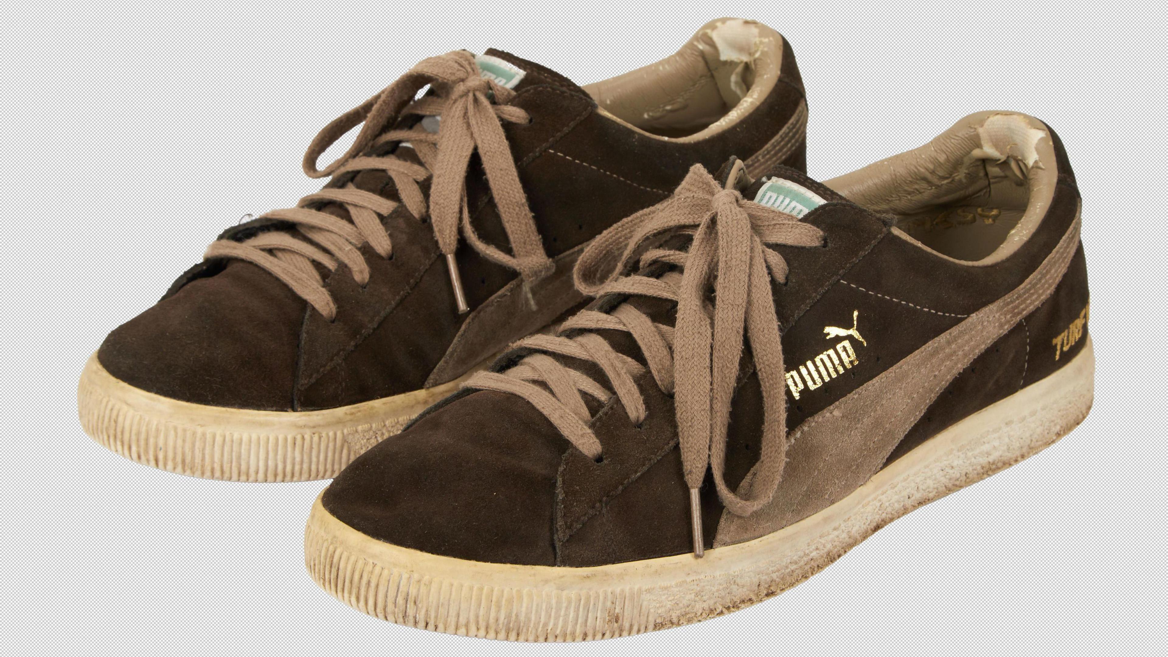 A pair of Puma trainers. They are brown and look worn.