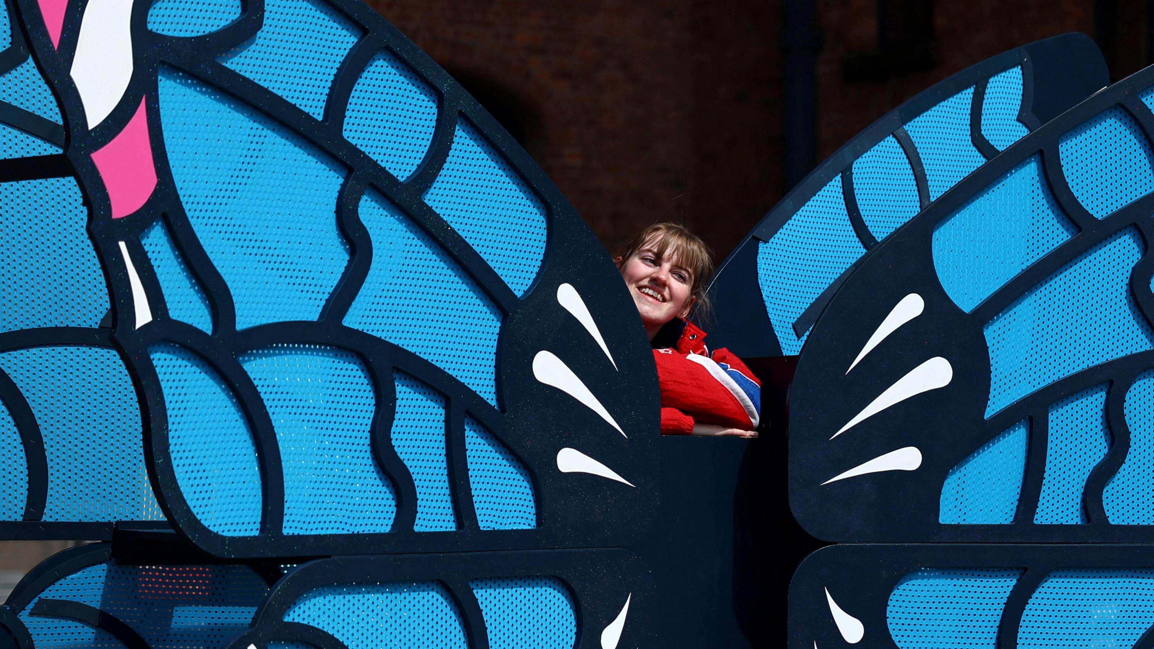 A fan poses next to a butterfly installation on the Taylor Swift trail 