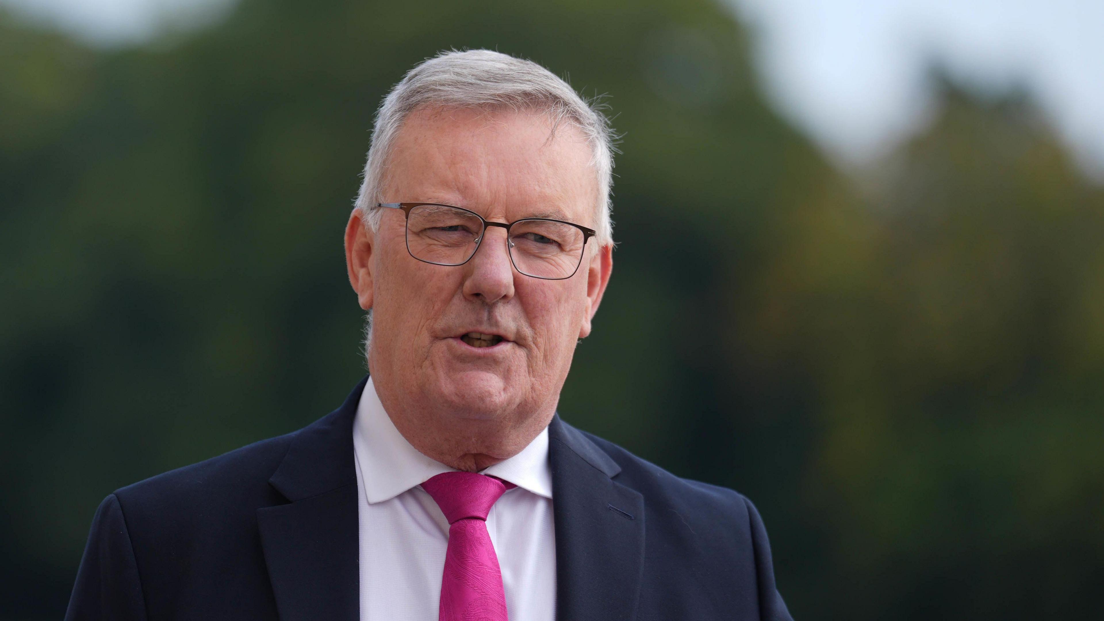 Health Minister Mike Nesbitt in a navy suit jacket white shirt and pink tie