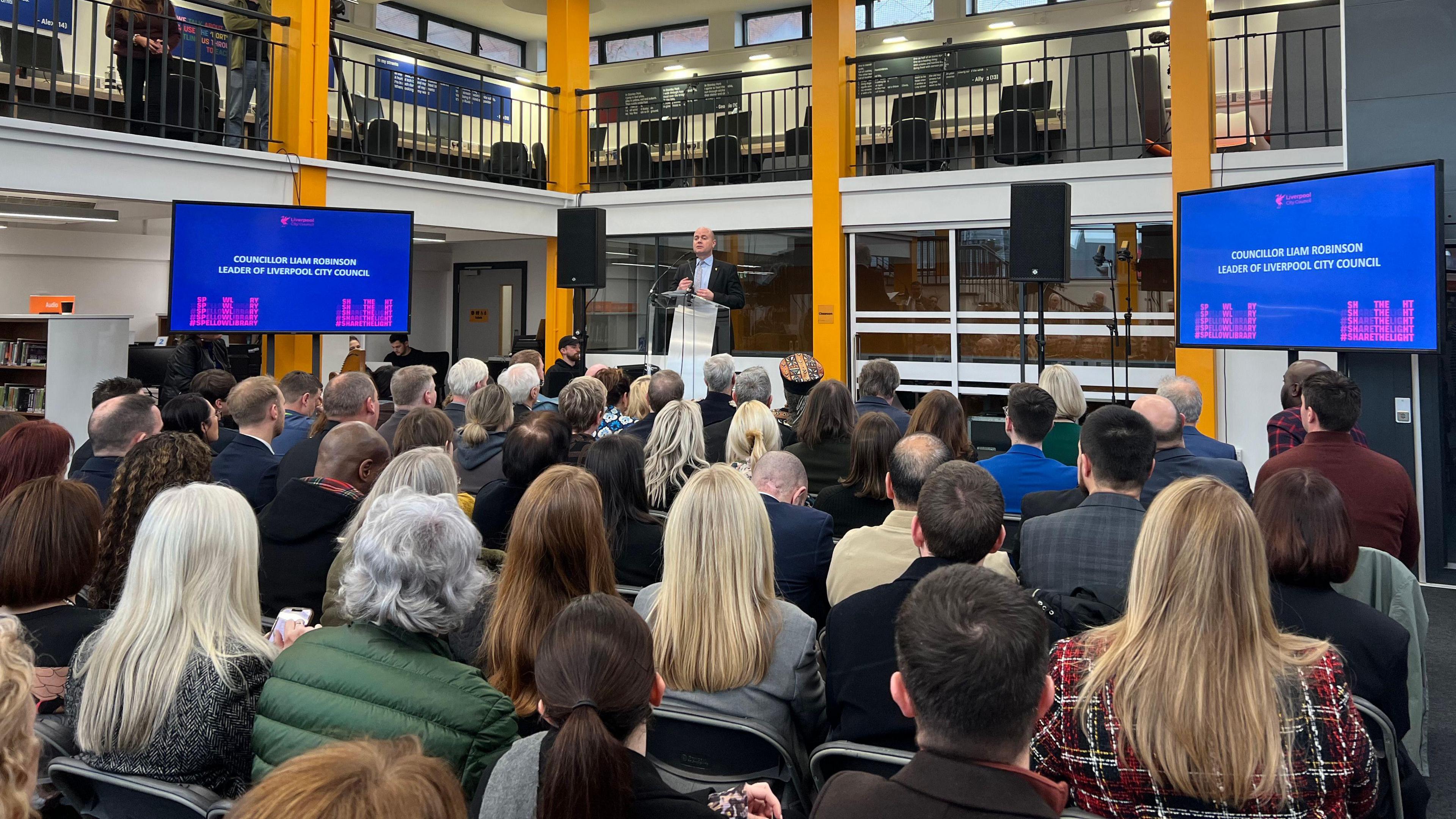 People sit and listen to a speech at Spellow Library during its reopening