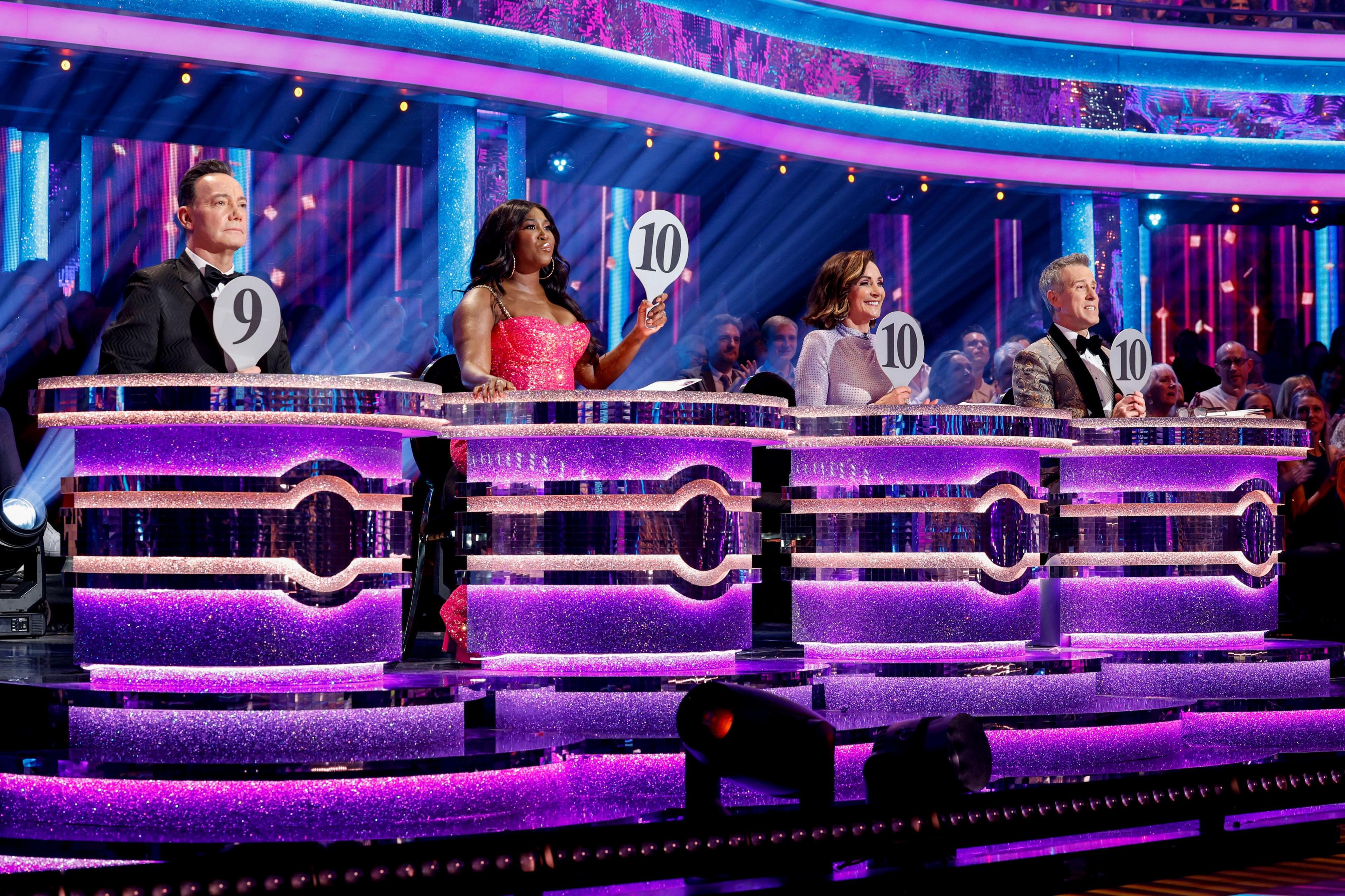 A picture showing the judges holding up scoring cards for the dancers