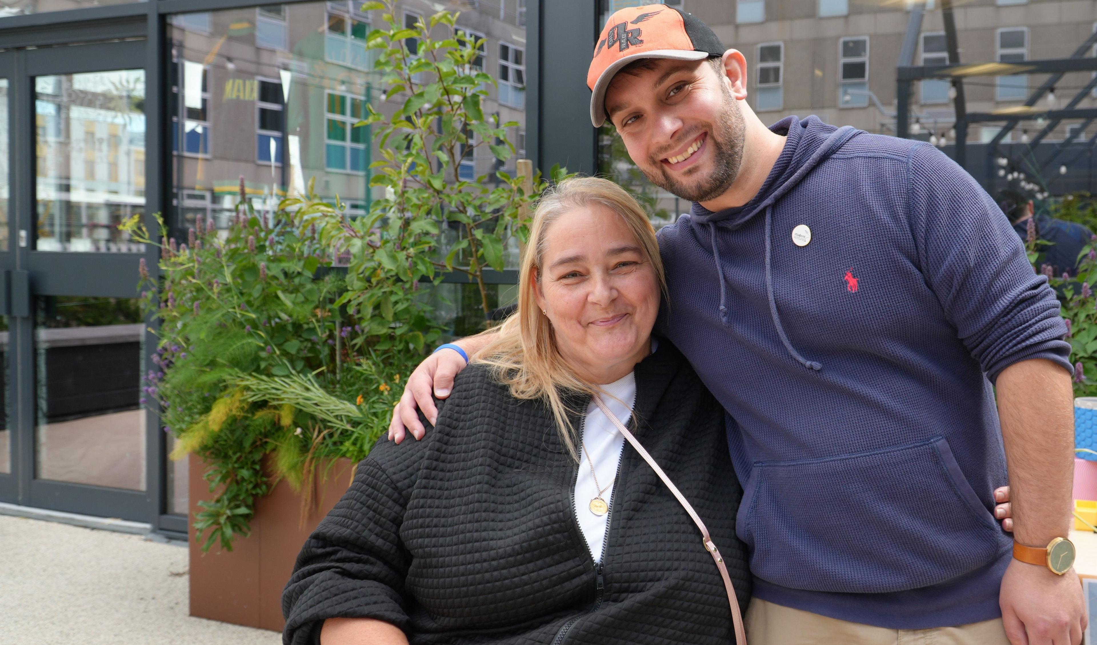 Michael Rose with his arm round Tanya Goddard, in front of a large window with a large plant next to it