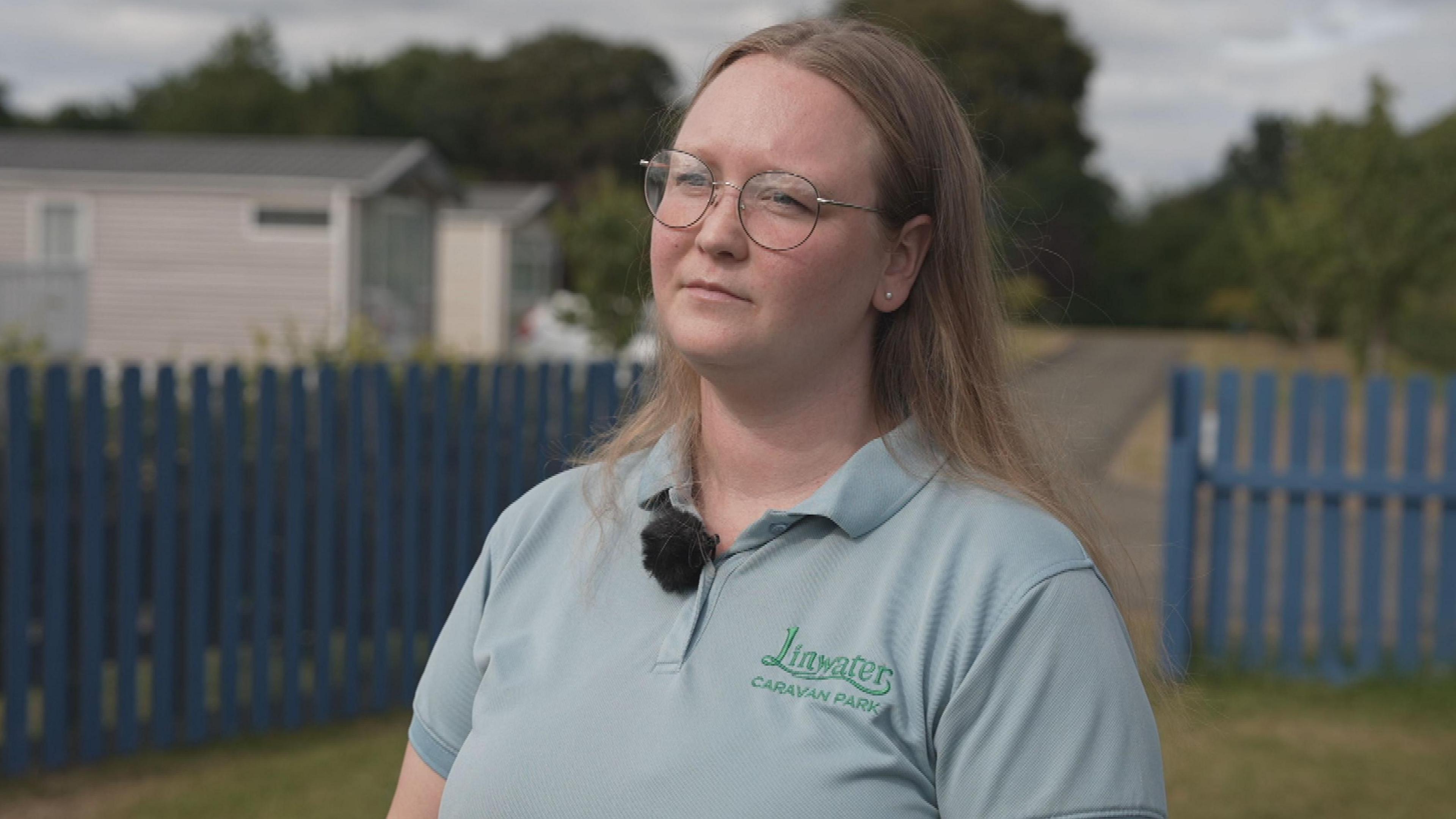 Ellie Jeffrey looking slightly off camera. She is wearing a grey polo shirt with a green logo on it.