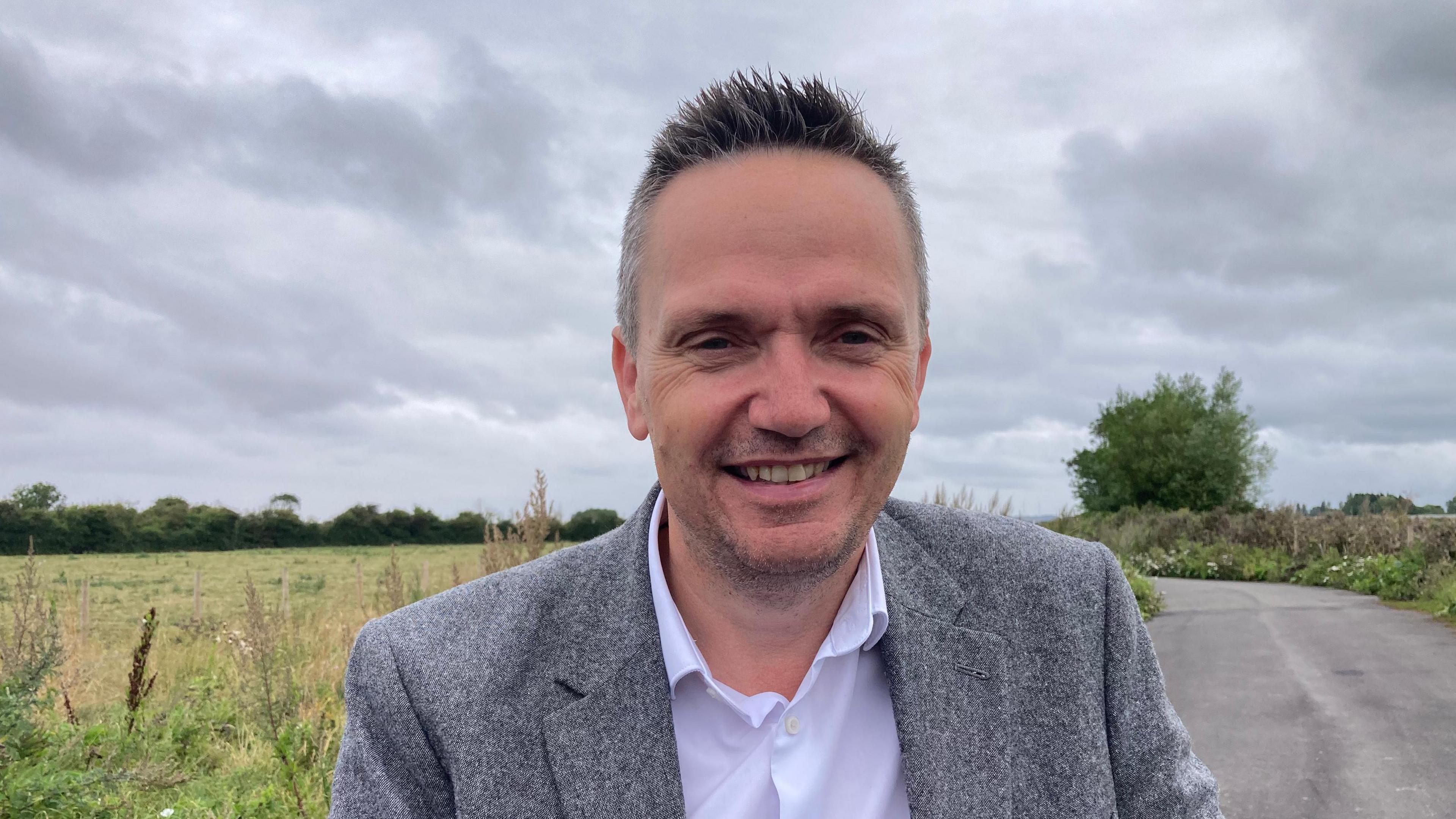 Mike Bell in a grey suit jacket by a cycle path