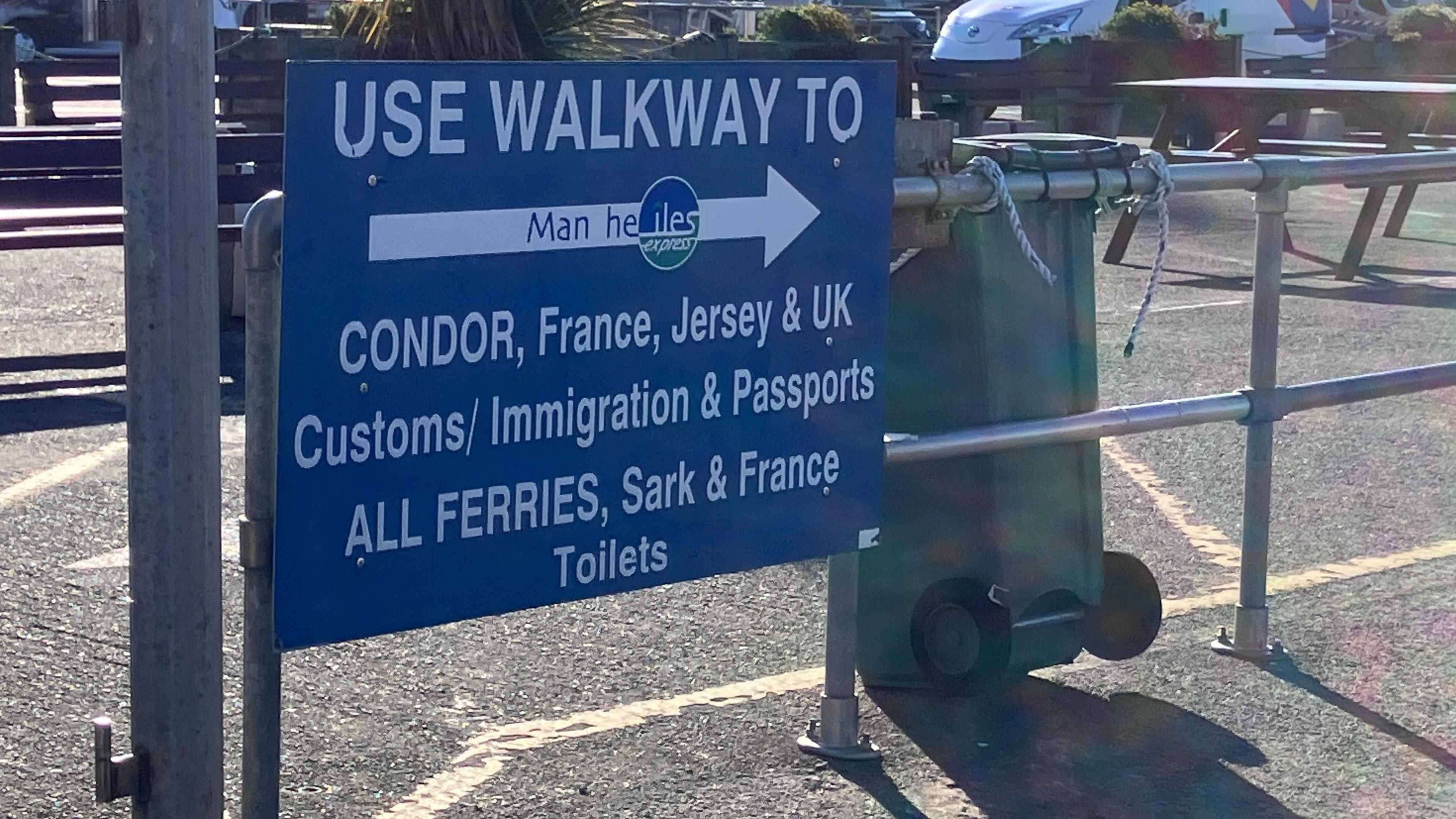Blue harbour sign with white writing and arrow directing people to customs and immigration