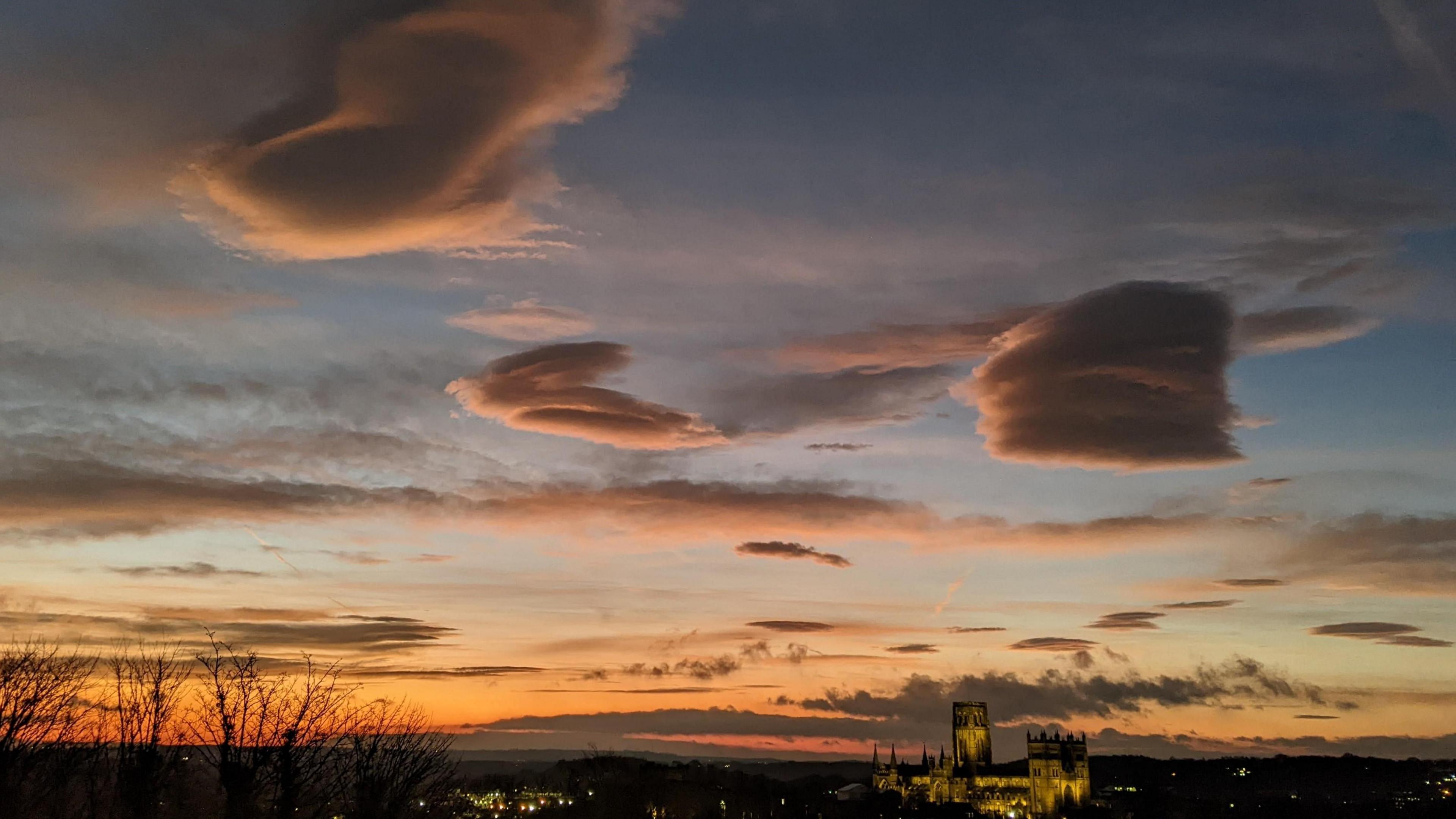 Clumps of orange-tinged clouds stand above the silhouette of a cathedral