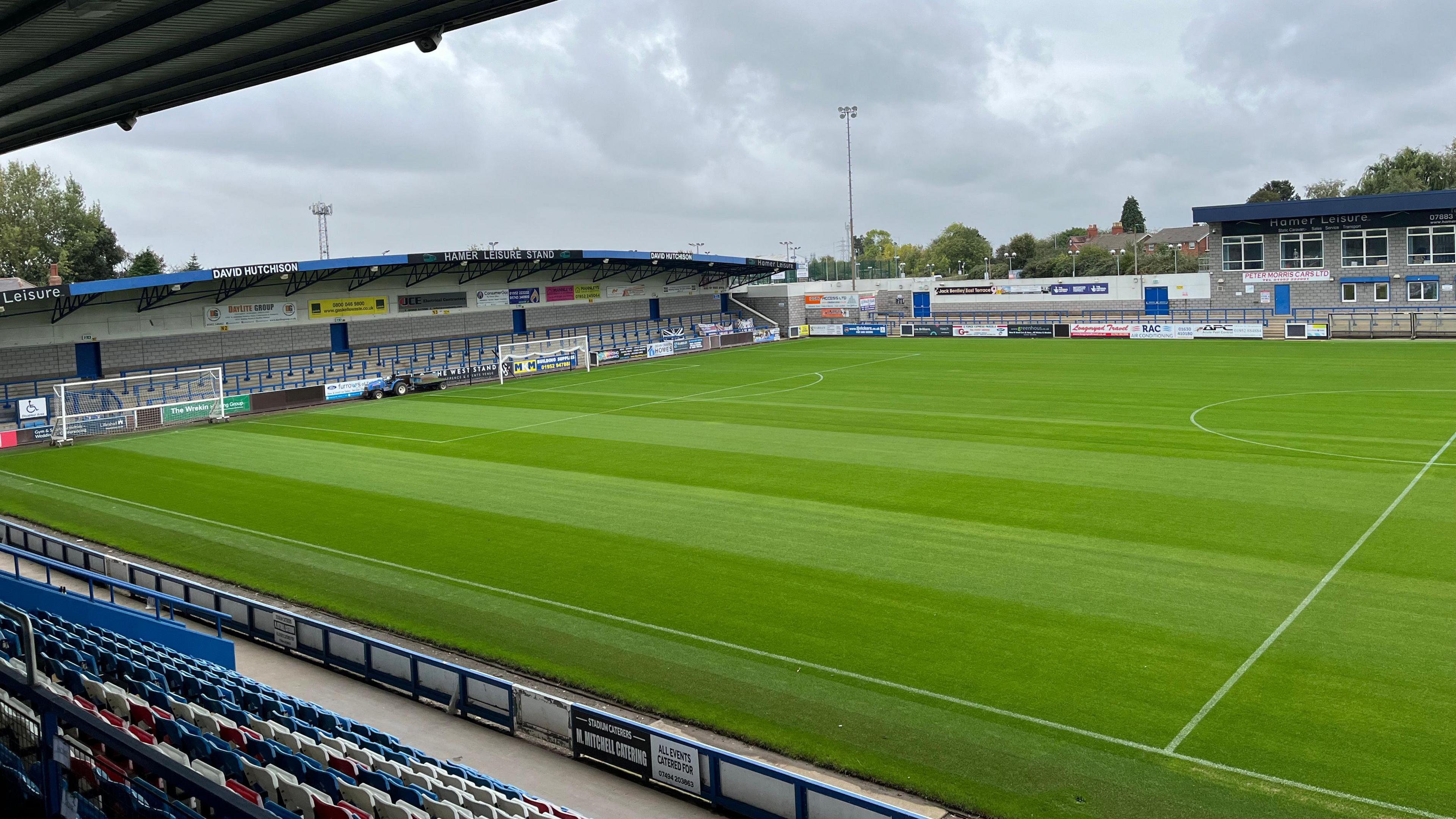 A football ground taken from the stands. The pitch is bright green 