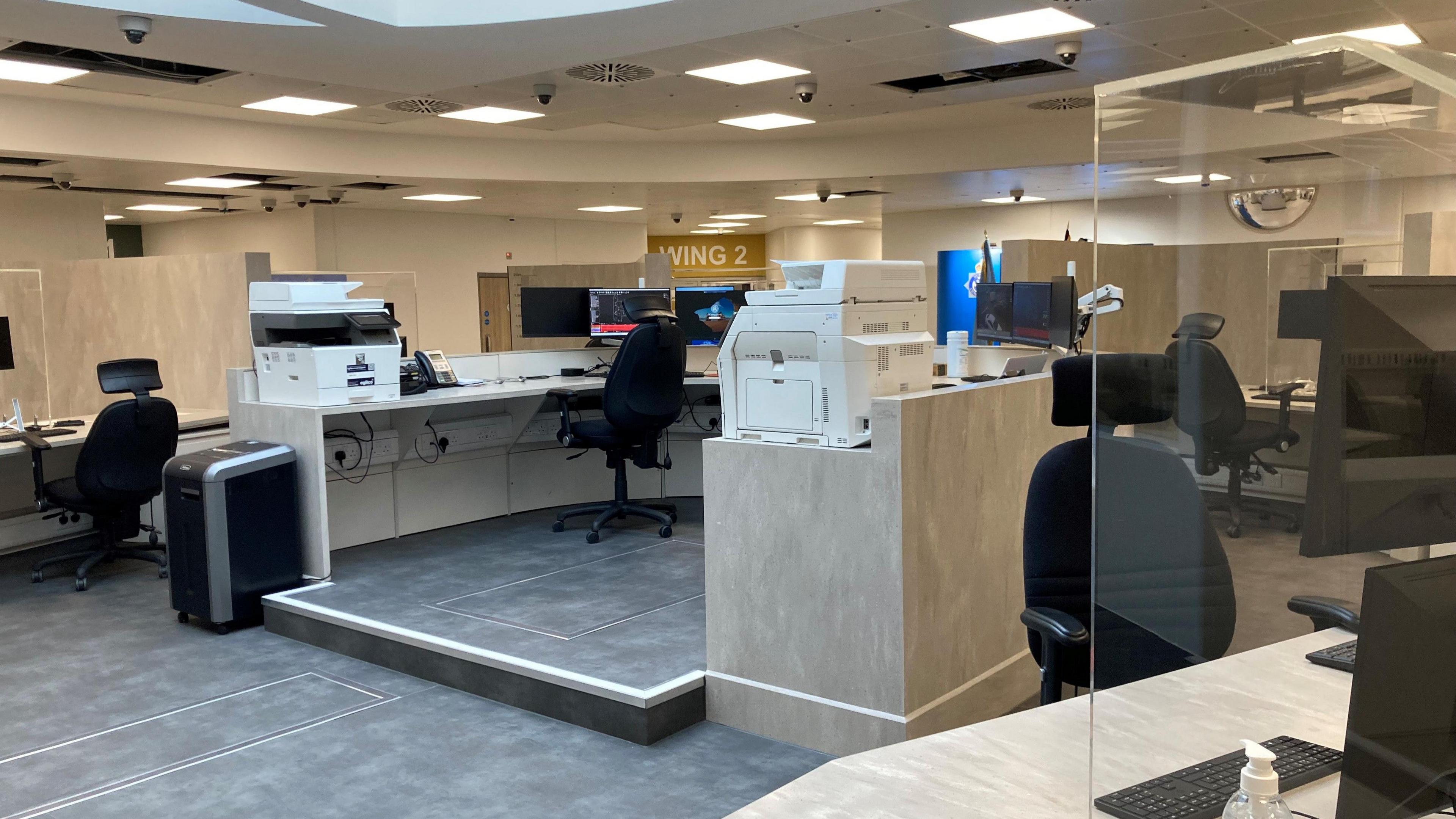 A new built and modern custody suite in Durham. There are several computers and chairs in separated booths.