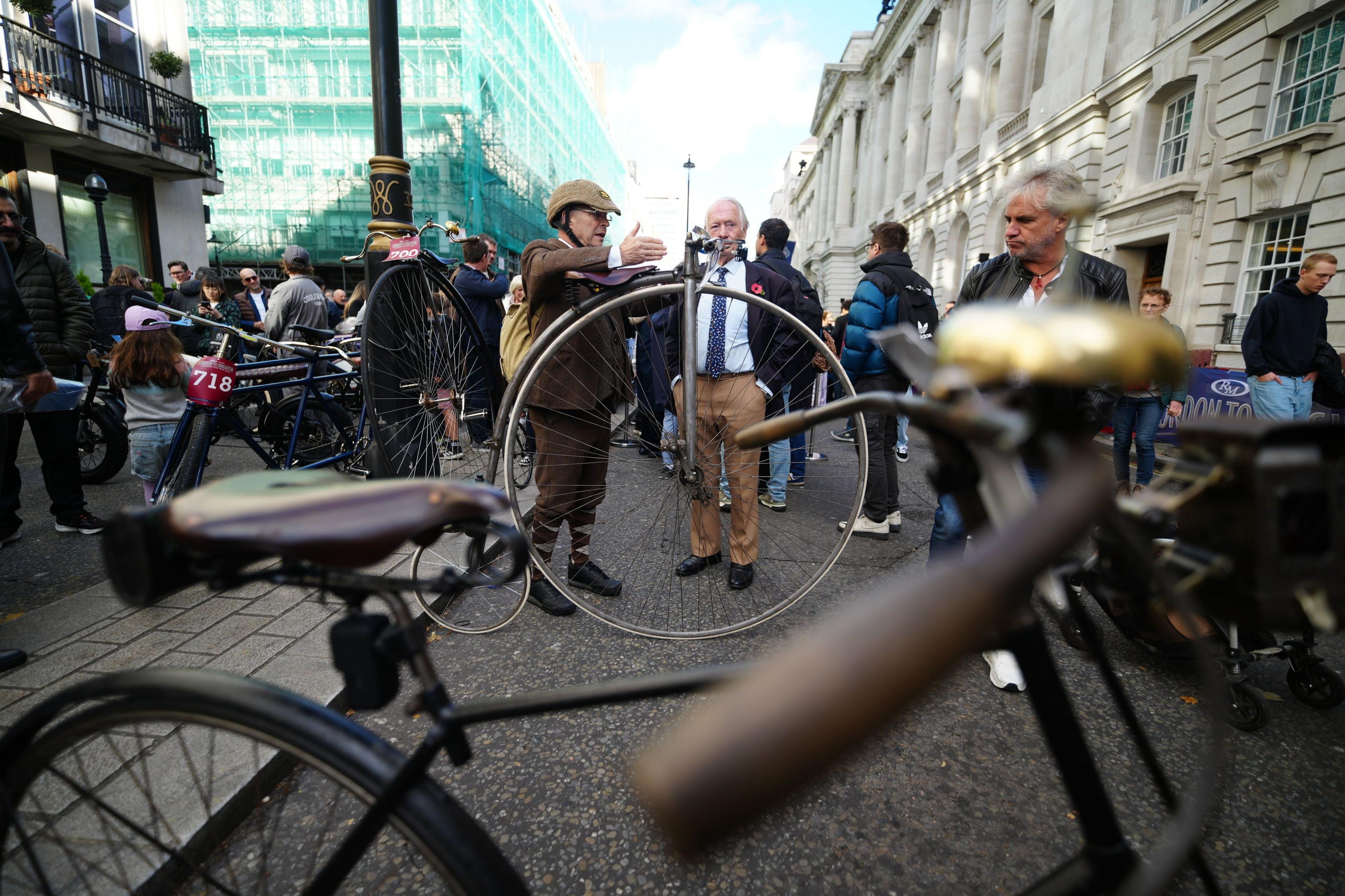 Old bikes, including a Penny Farthing, are looked at by men in suits