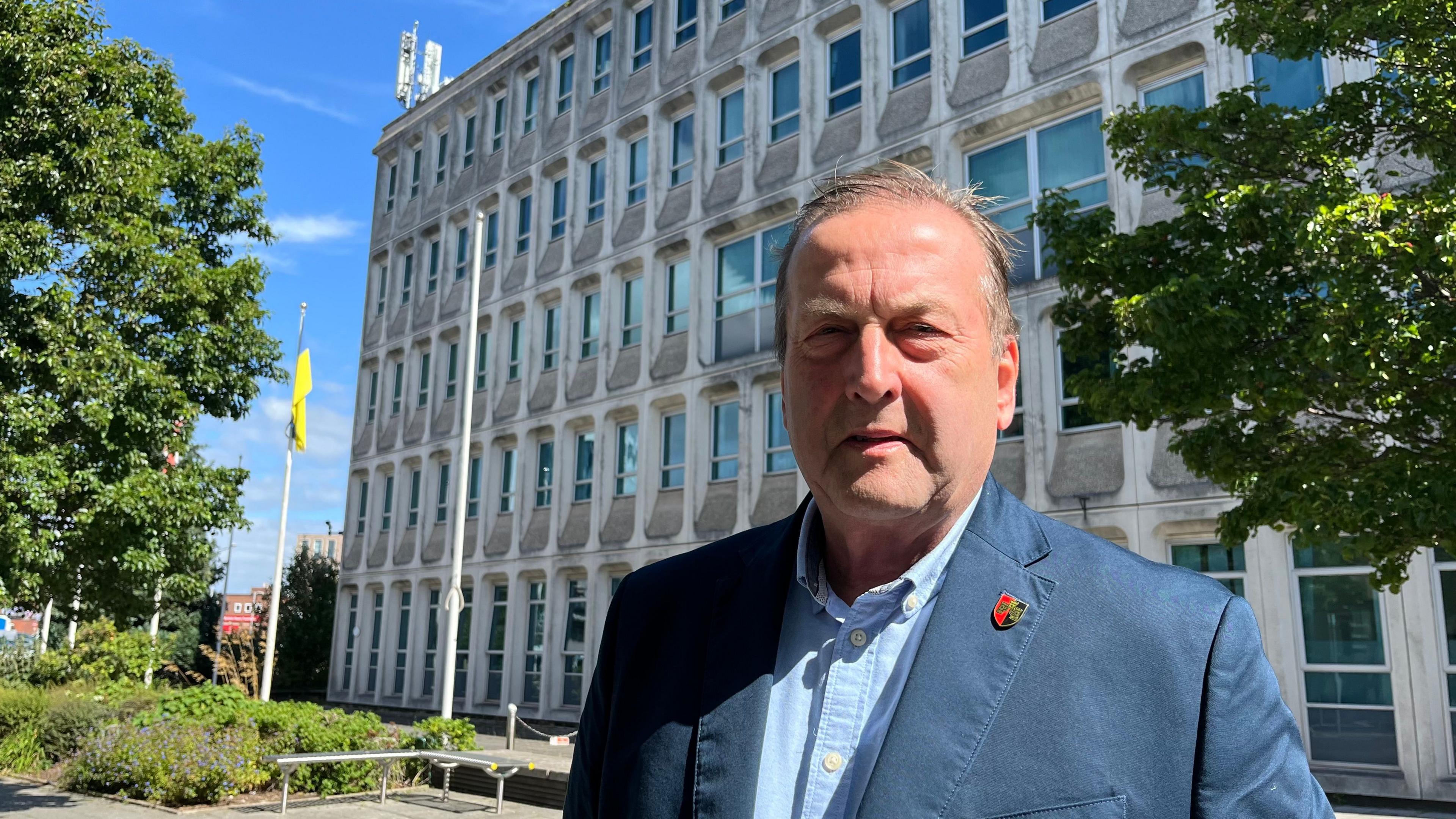 Phil Bialyk, leader of Exeter City Council, wearing a blue shirt and jacket, standing in front of the Civic Centre