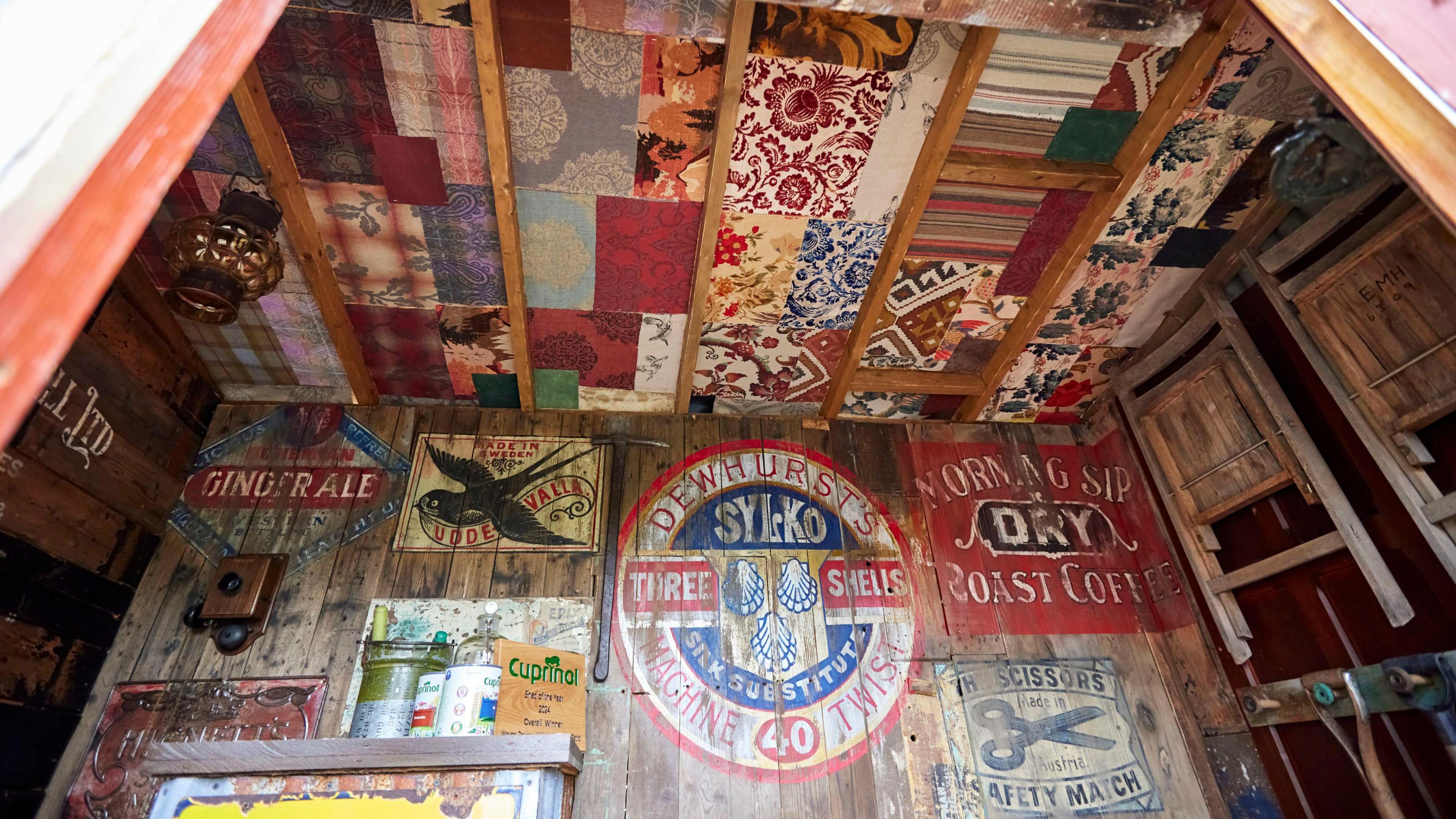 Brightly coloured designs painted on the wooden inside of a shed with a patterned ceiling.