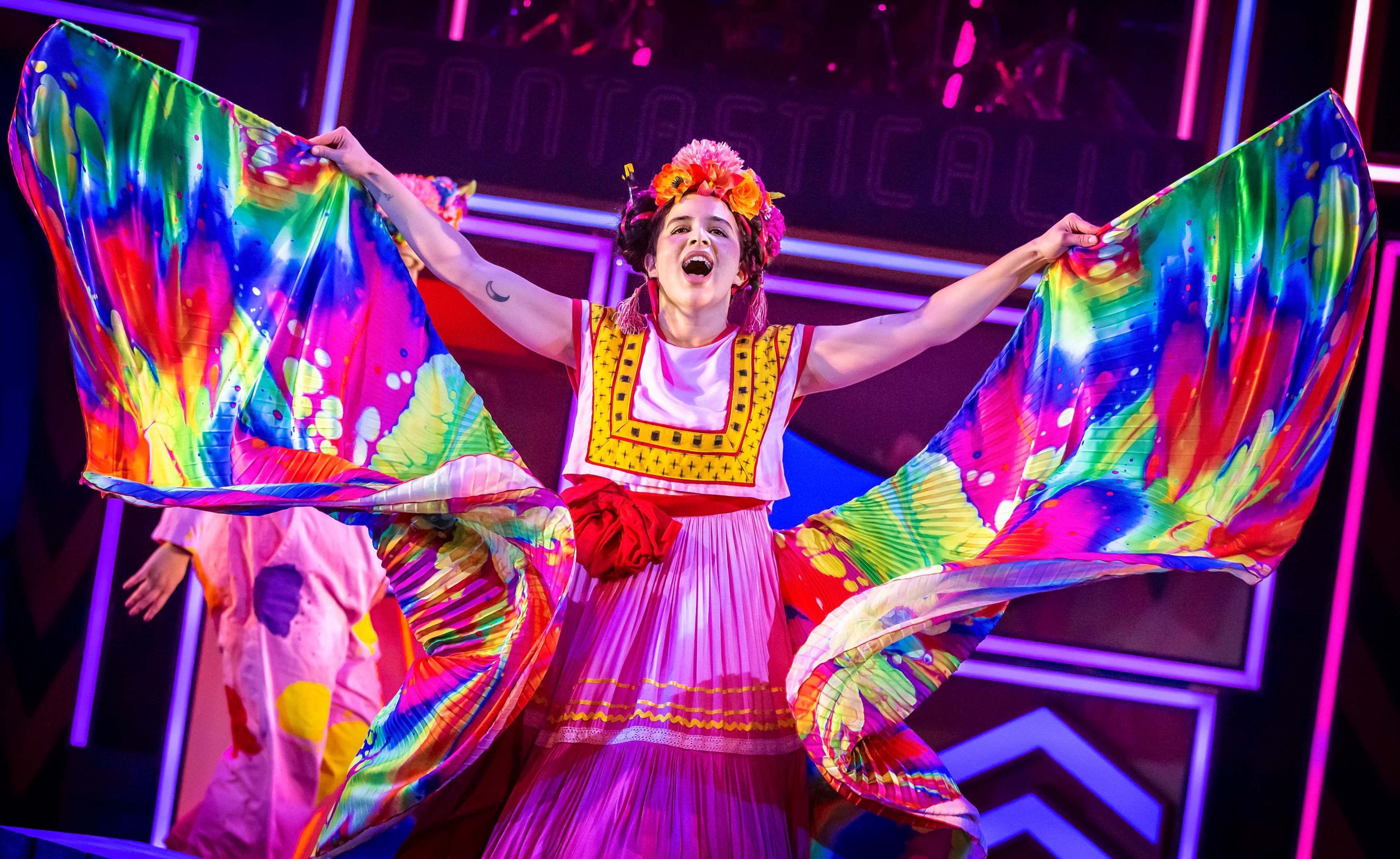 Elena Breschi dressed in a billowing brightly coloured outfit portraying artist Frida Kahlo