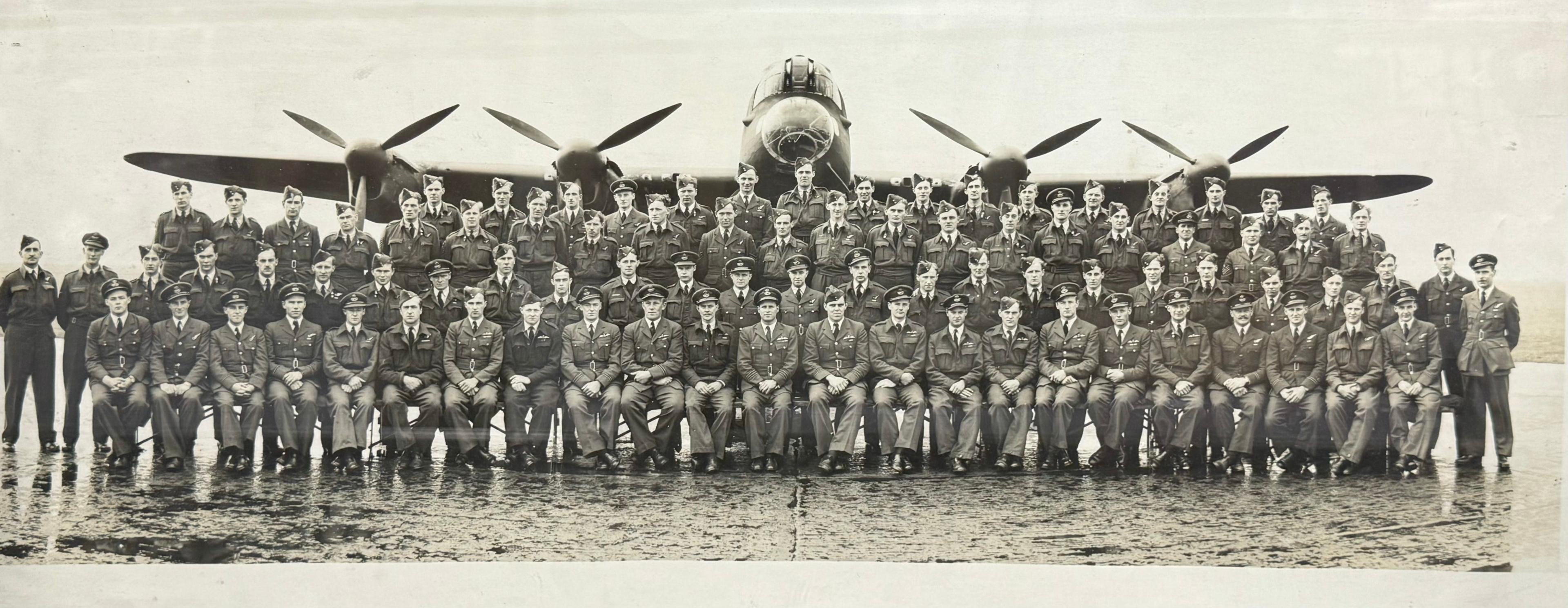 Black and white photograph of RAF personnel posed in front of a Lancaster bomber, with its cockpit, wings and four engines in view.