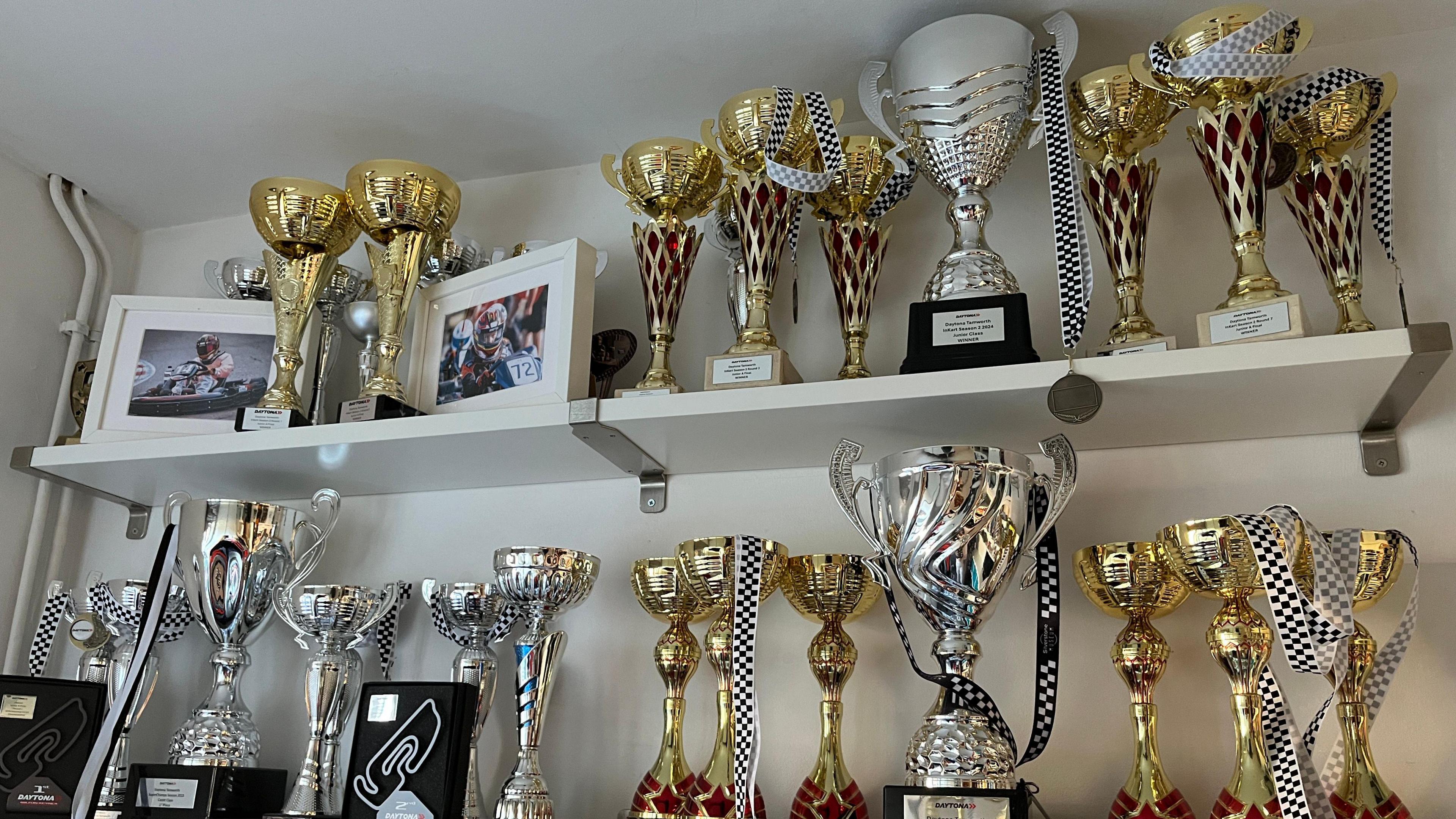 Gold and silver trophies line the shelves along with photo frames