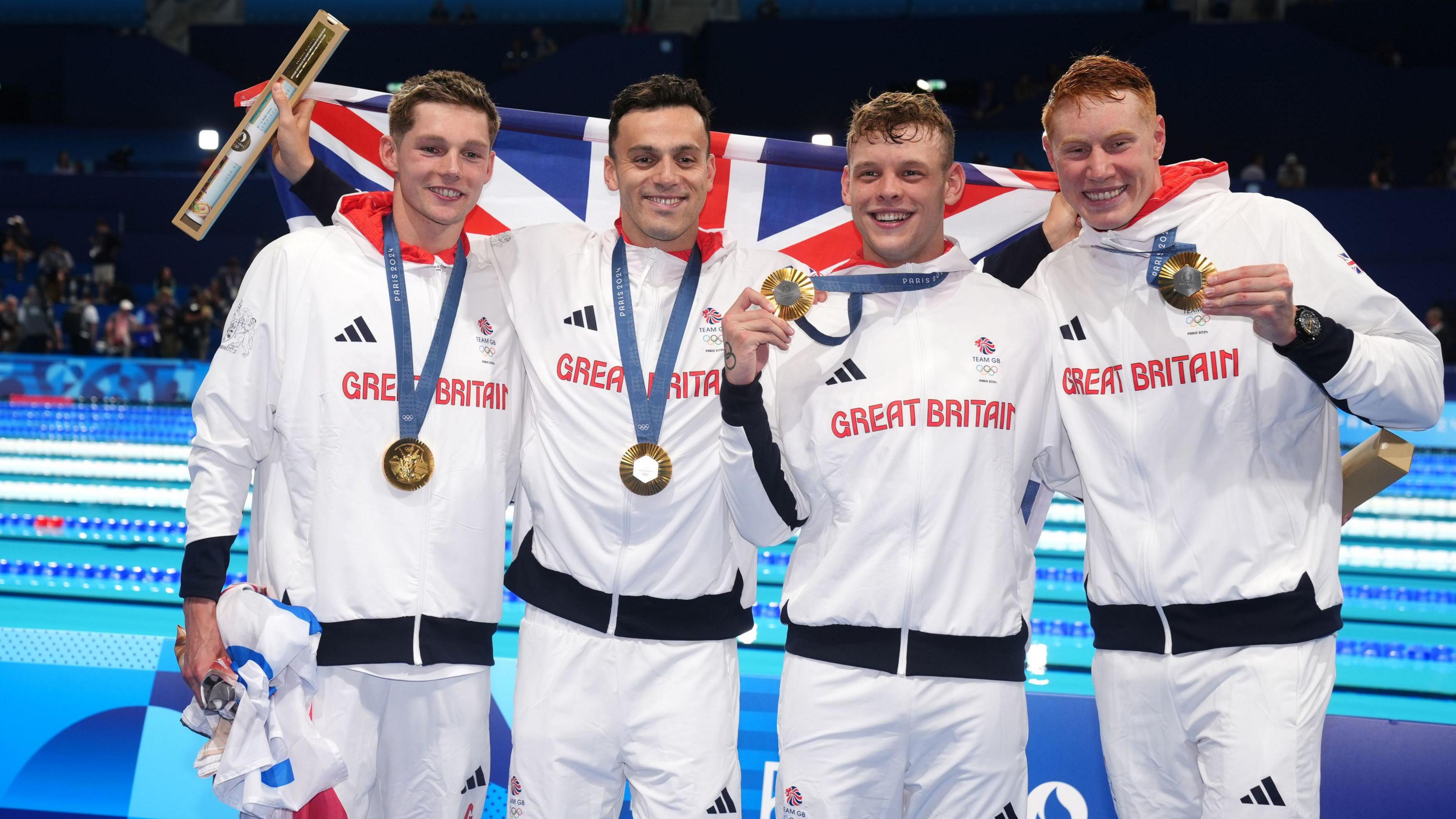 Great Britain's Duncan Scott, James Guy, Matthew Richards and Tom Dean pose with their gold medals after winning the Men's 4 x 200m Freestyle Relay Final at the Paris La Defense Arena wearing their Great Britain tracksuits