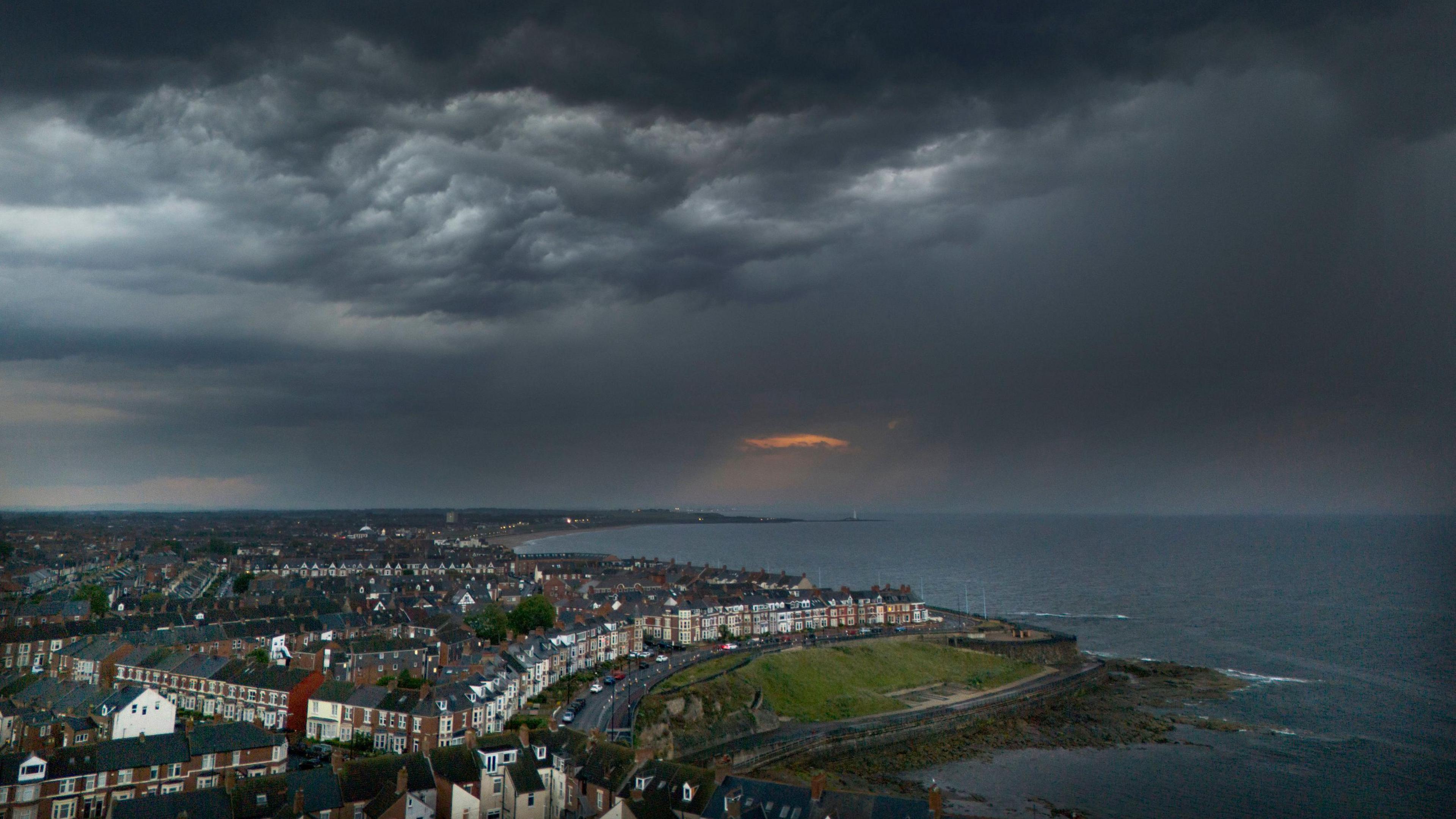 A landscape image of Whitley Bay in North Tyneside along the coastline. Dark clouds have gathered across the sky.