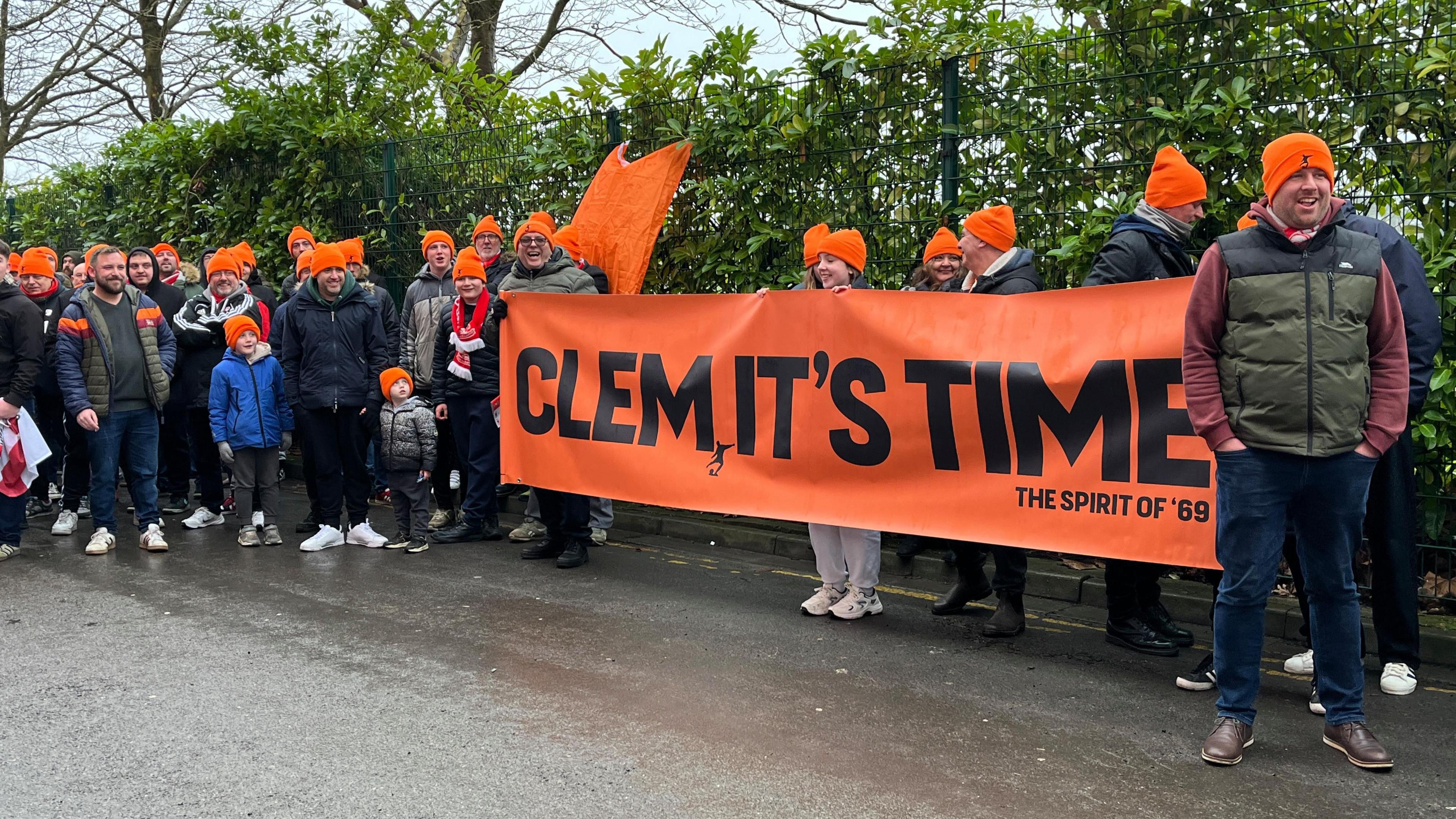 Protesters for the Spirit of '69 group holding an orange banner which says "Clem it's time" and wearing orange hats