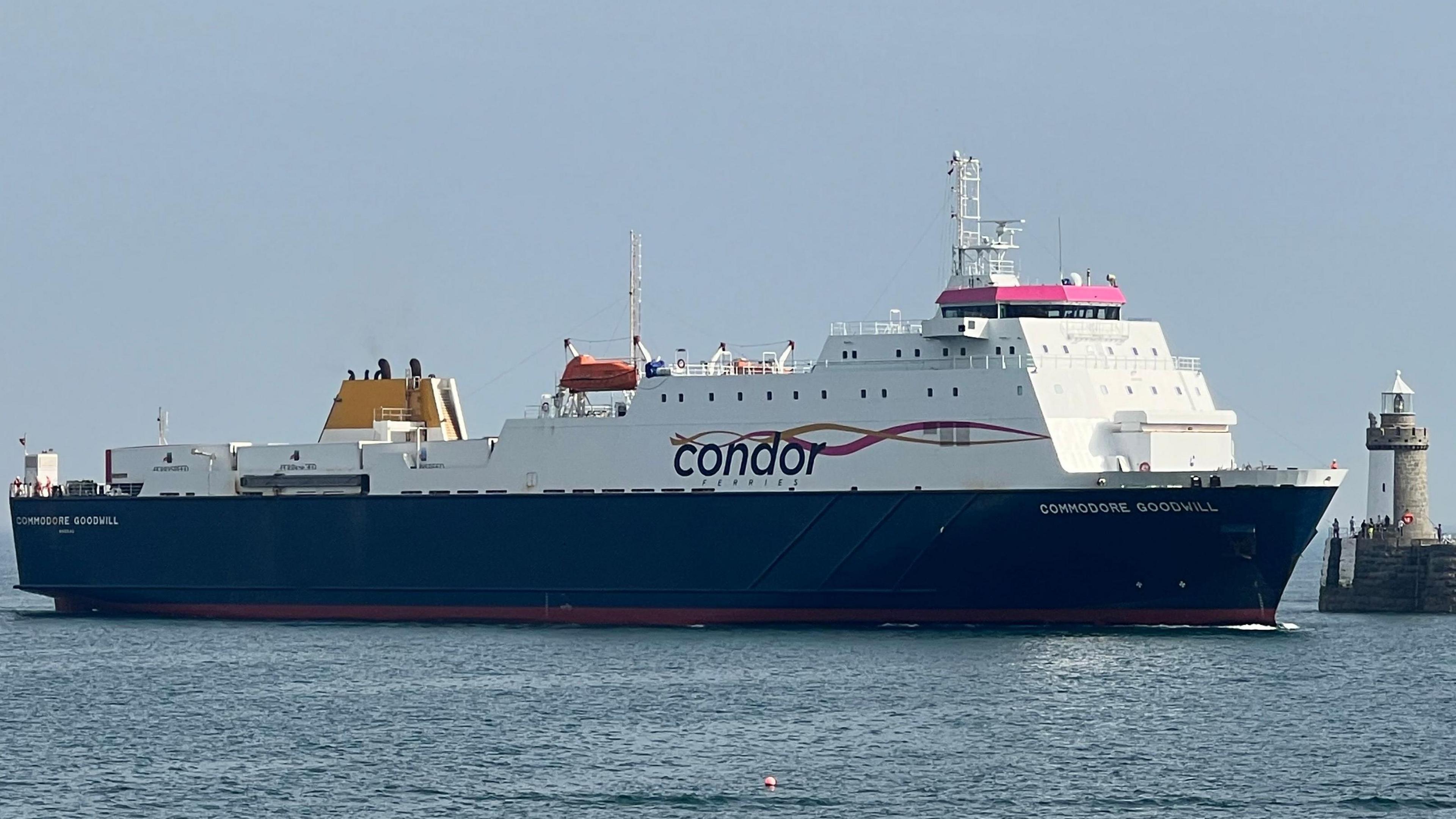 A large commercial vessel, the Commodore Goodwill, heading into a harbour. Skies are blue.
